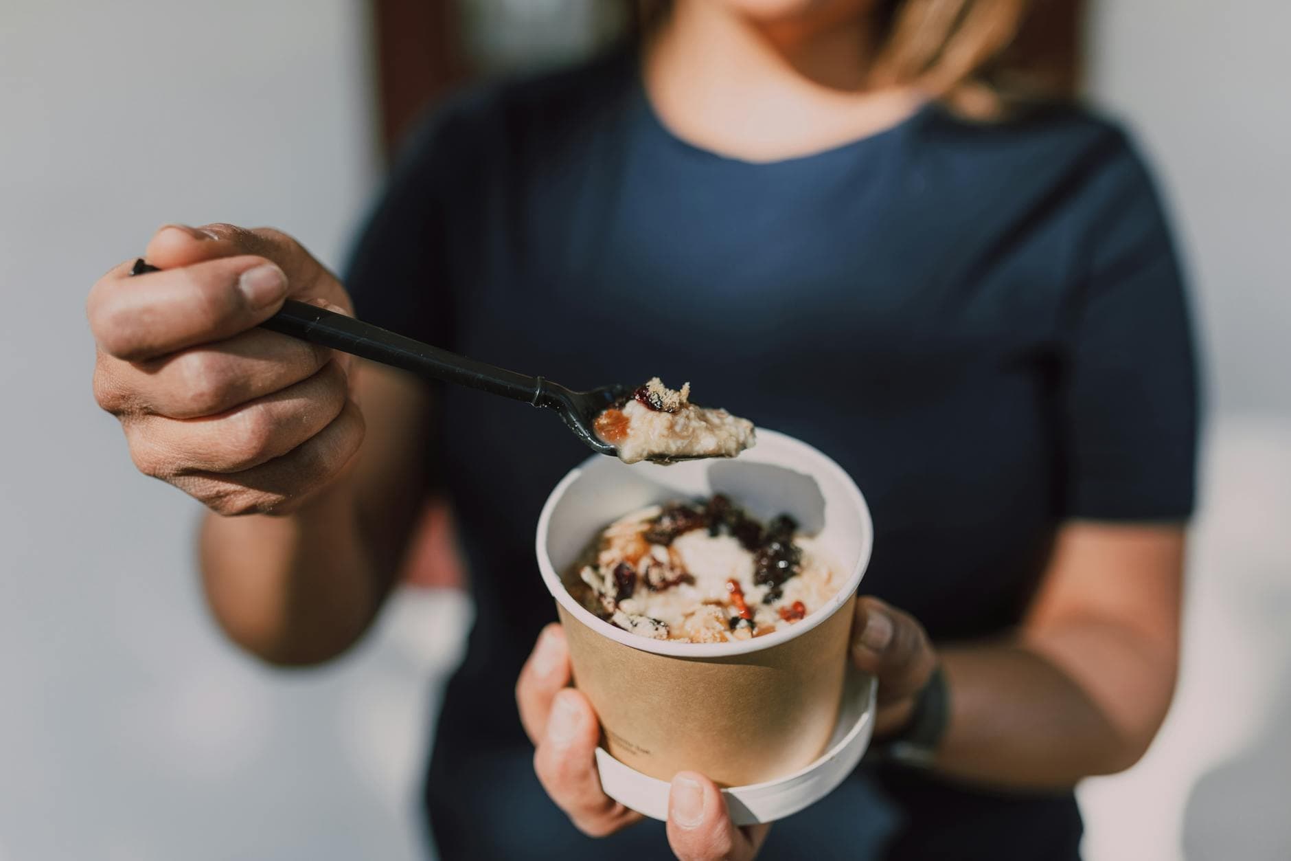 Close-up of a person holding a bowl of vegan oatmeal topped with fruits. - best gut health foods