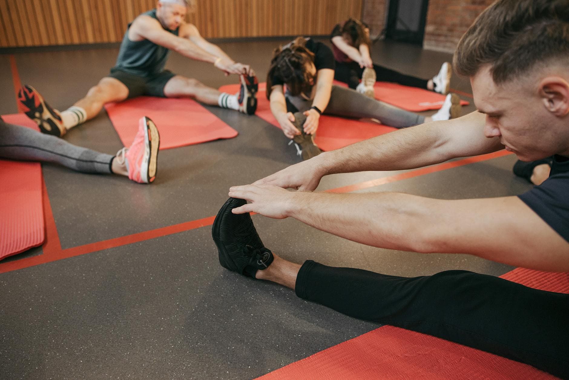 Adults participating in fitness stretching session indoors, enhancing flexibility on red yoga mats. - dynamic flexibility exercises