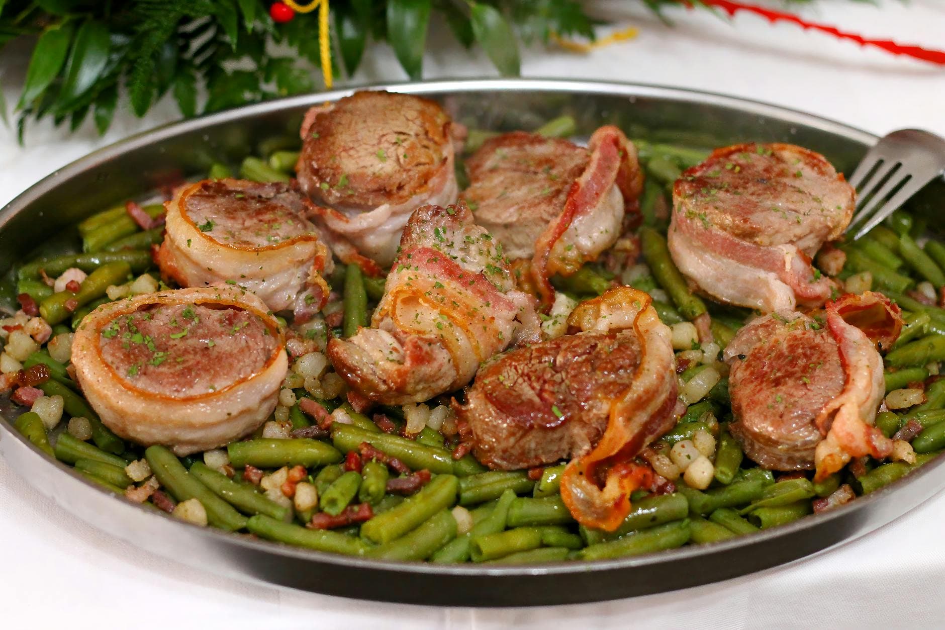 Delicious bacon-wrapped pork medallions served on a bed of seasoned green beans and beans. - easy dinner recipes