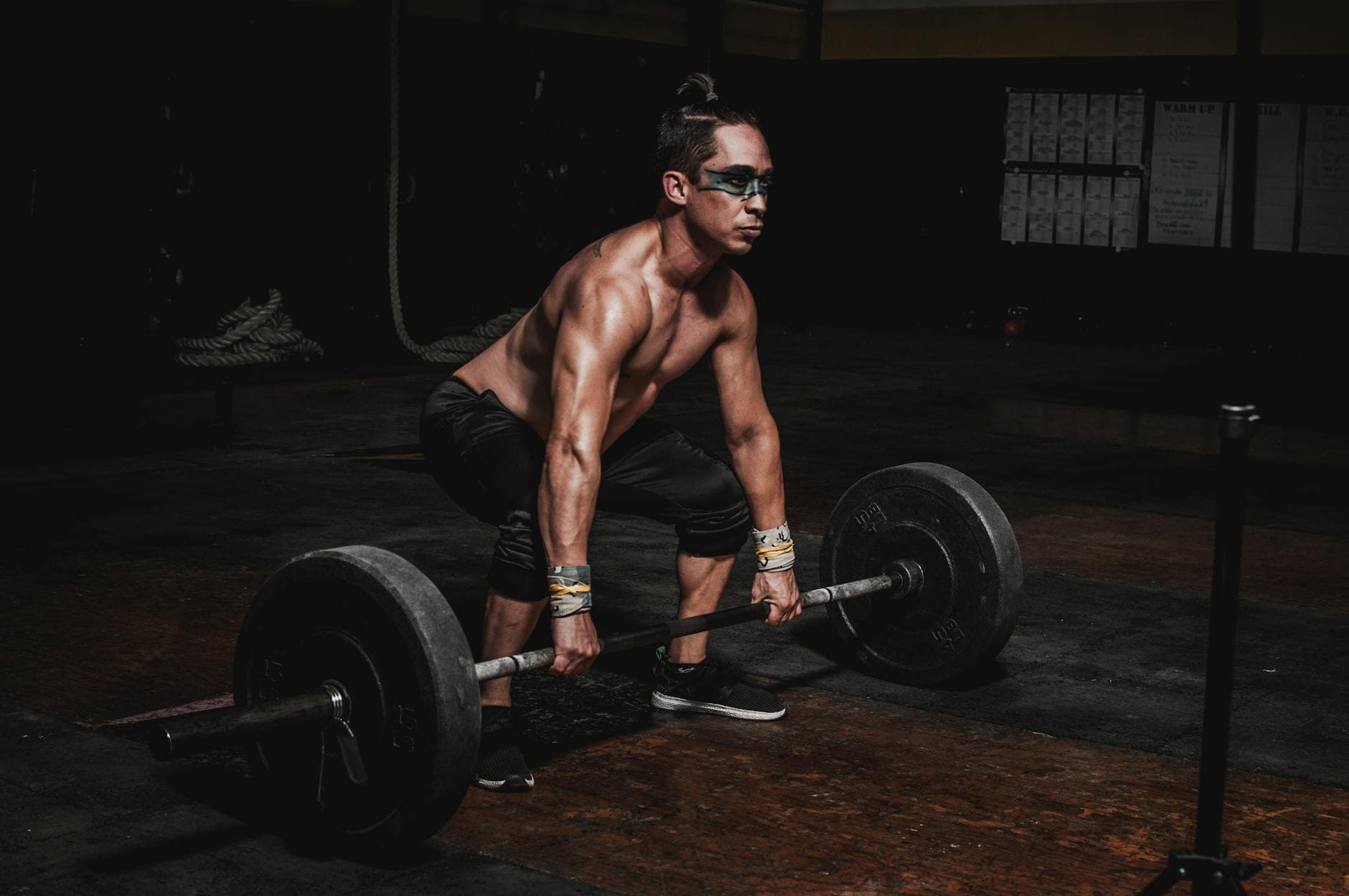 Strong athlete lifting heavy barbell in a dimly lit gym, showcasing strength and determination. - full body weight workout