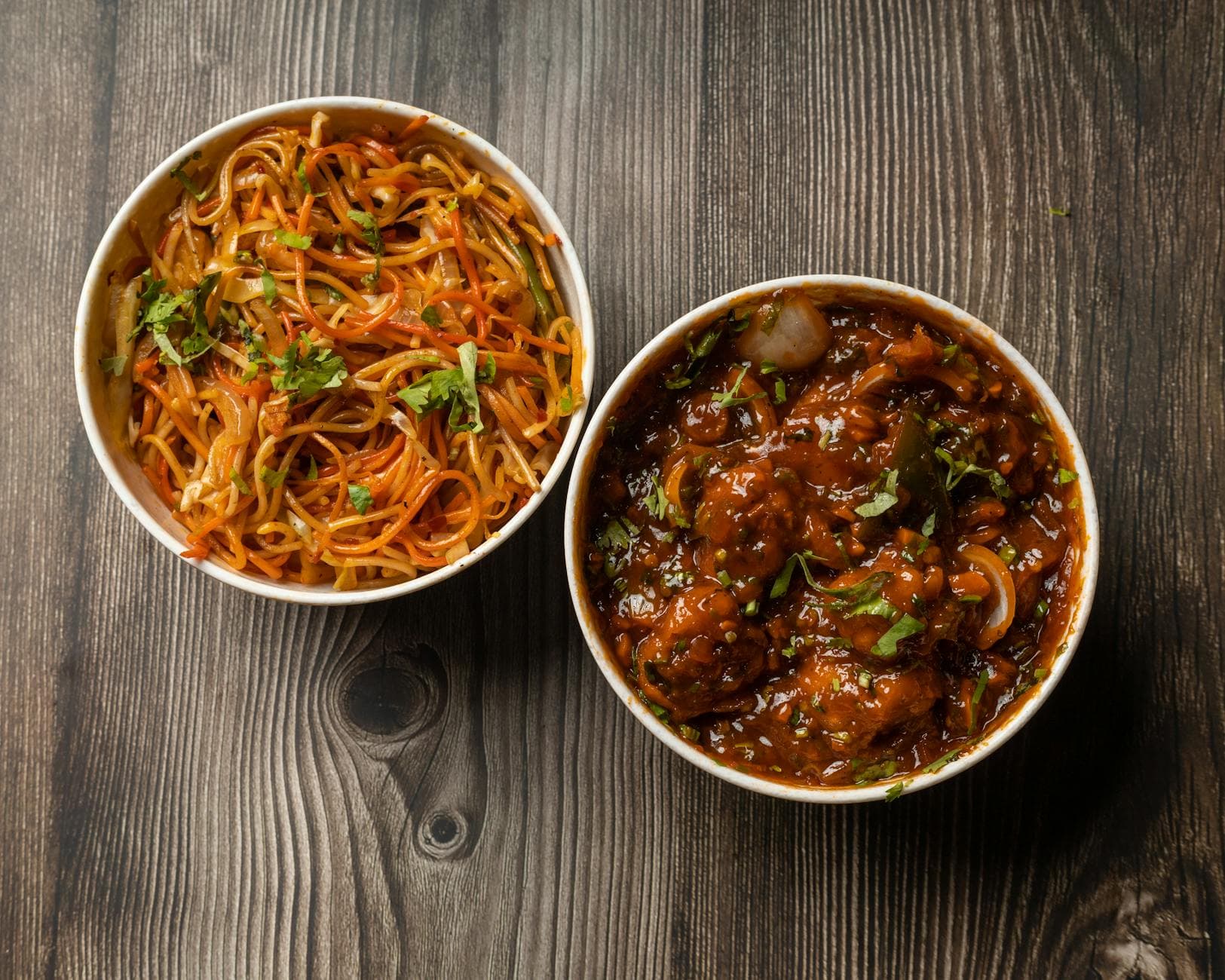 Vibrant bowls of Indo-Chinese noodles and Manchurian on a rustic wooden surface. - healthy dinners for two