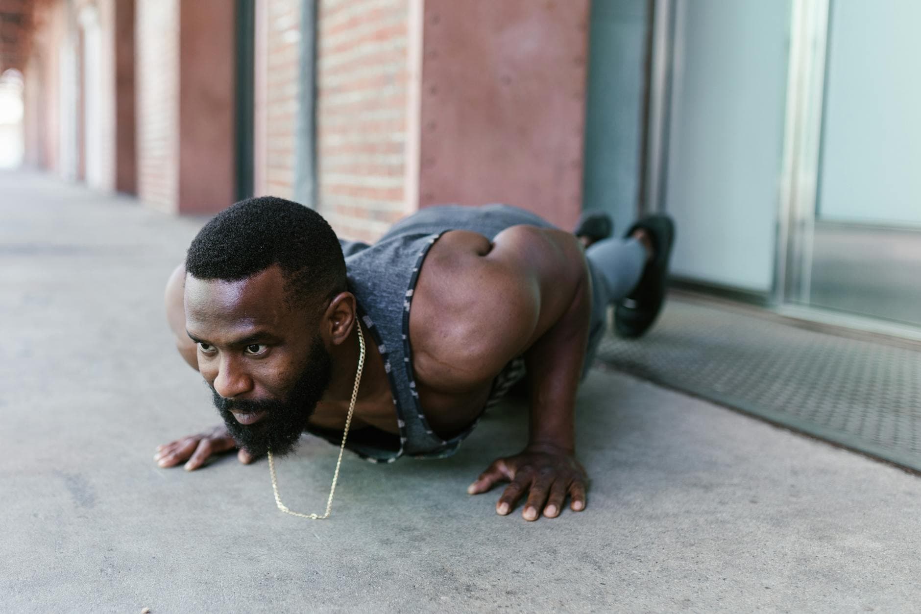 An athletic man exercises with a push-up in urban surroundings, showcasing strength and fitness. - men's workout routine