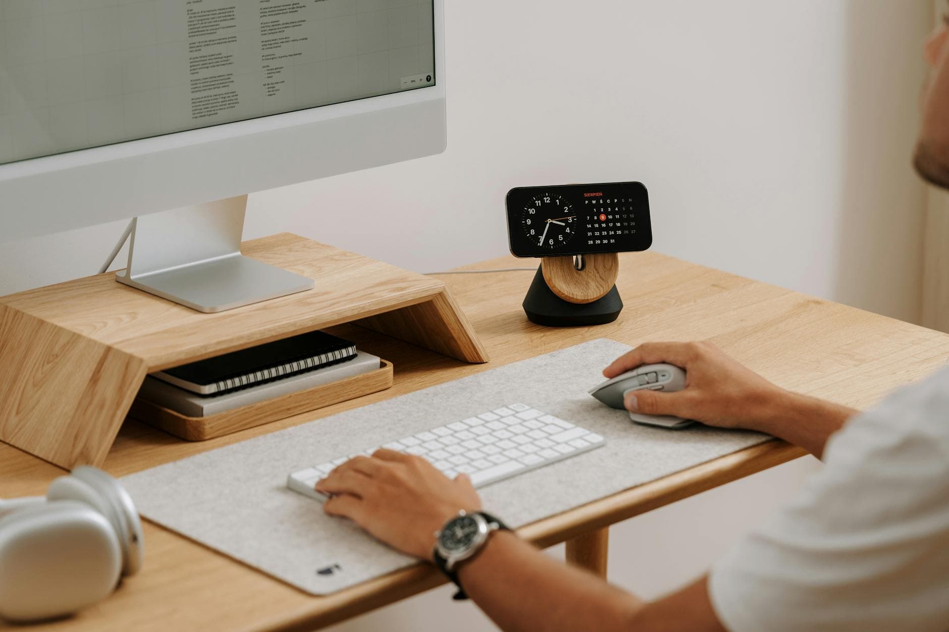 A clean and modern desk setup featuring a computer, clock, and accessories in a home office. - standing desk exercises