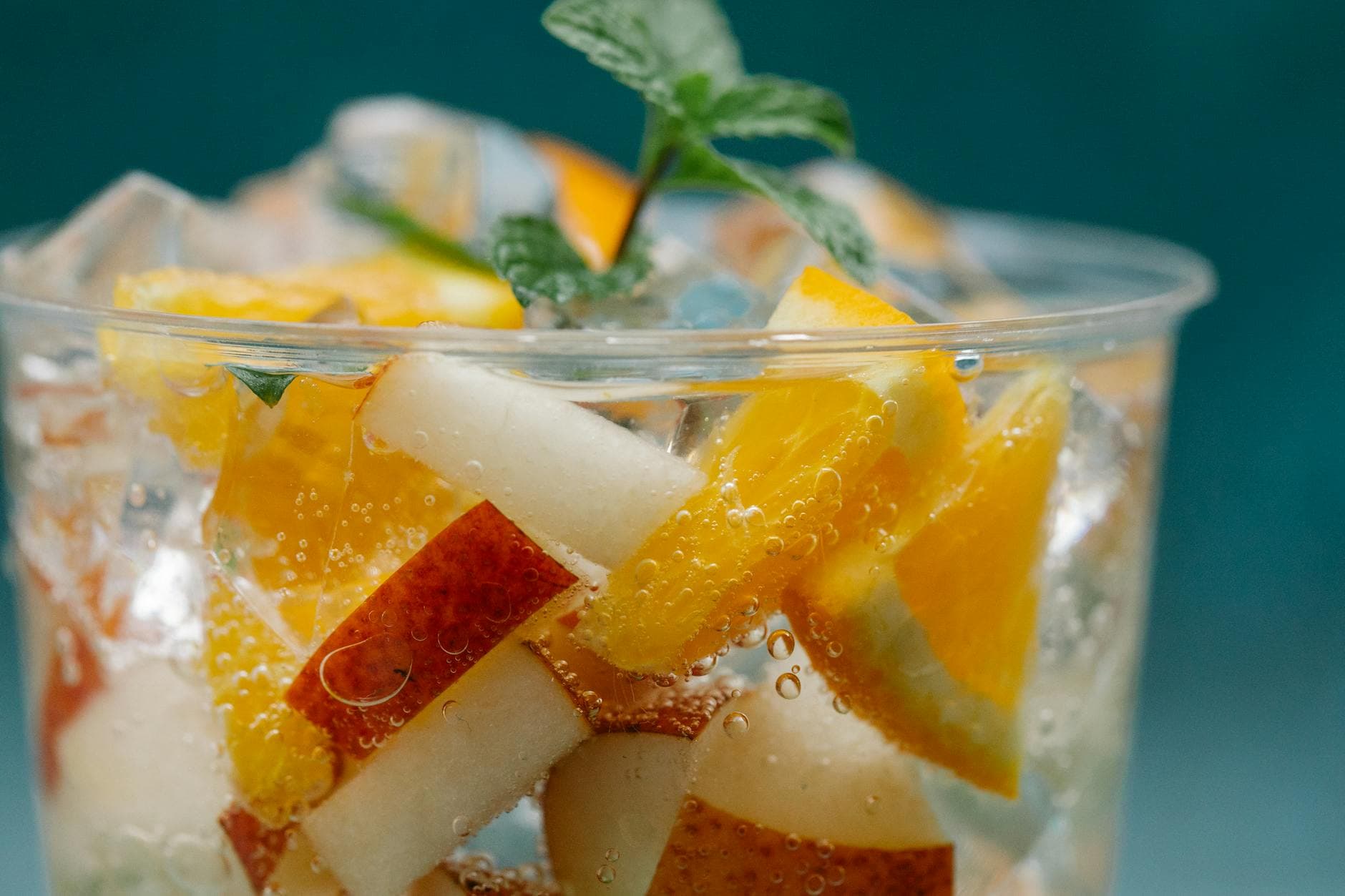 Close-up of a refreshing citrus and apple infused drink with ice in a cup. - apple detox water