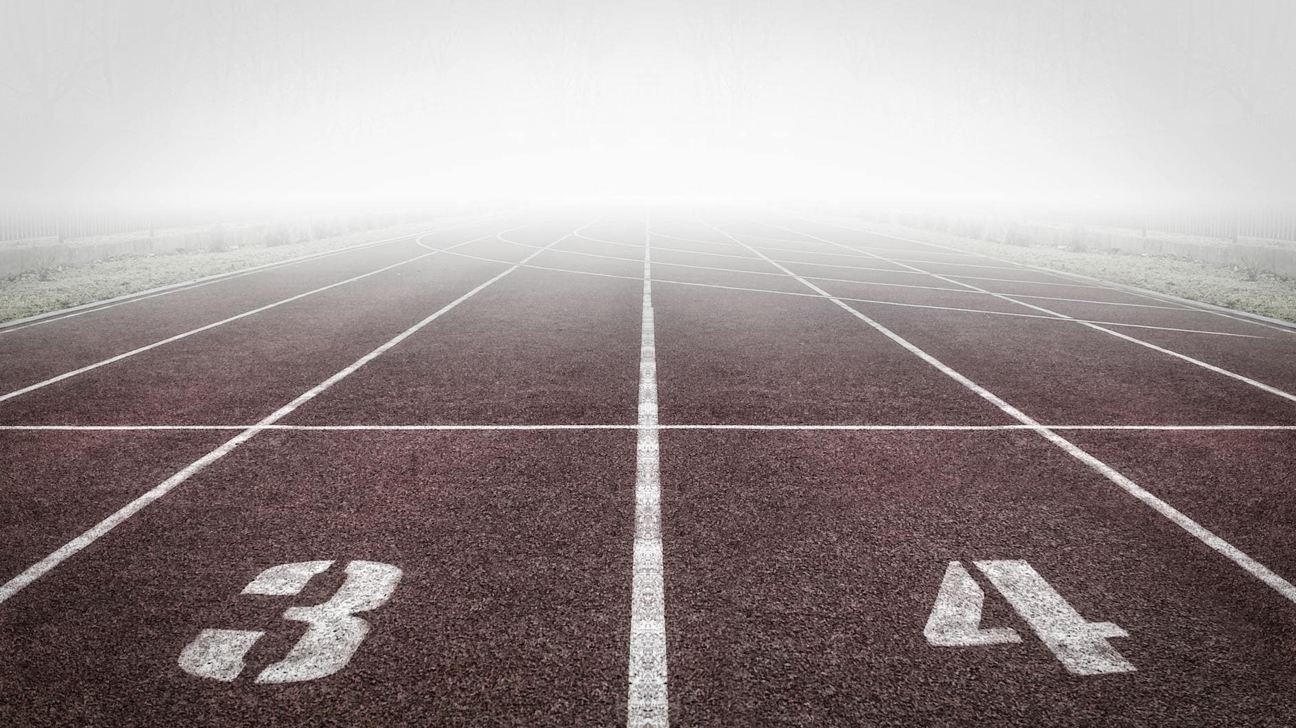 A foggy track field with visible lane numbers and white lines. - beginner running plan