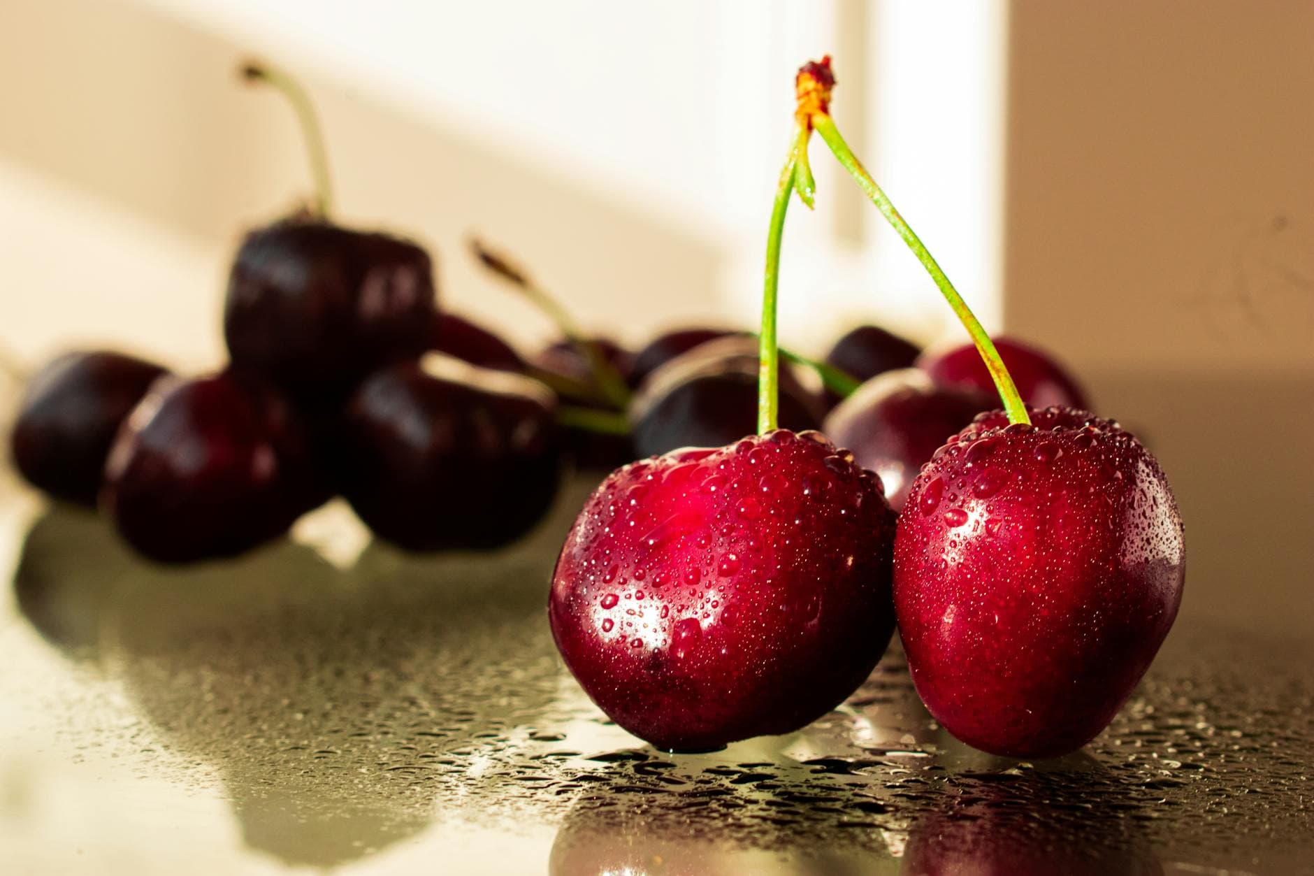 Close-up view of fresh, dewy cherries on a reflective surface, highlighting their vibrant color and freshness. - cucumber water benefits