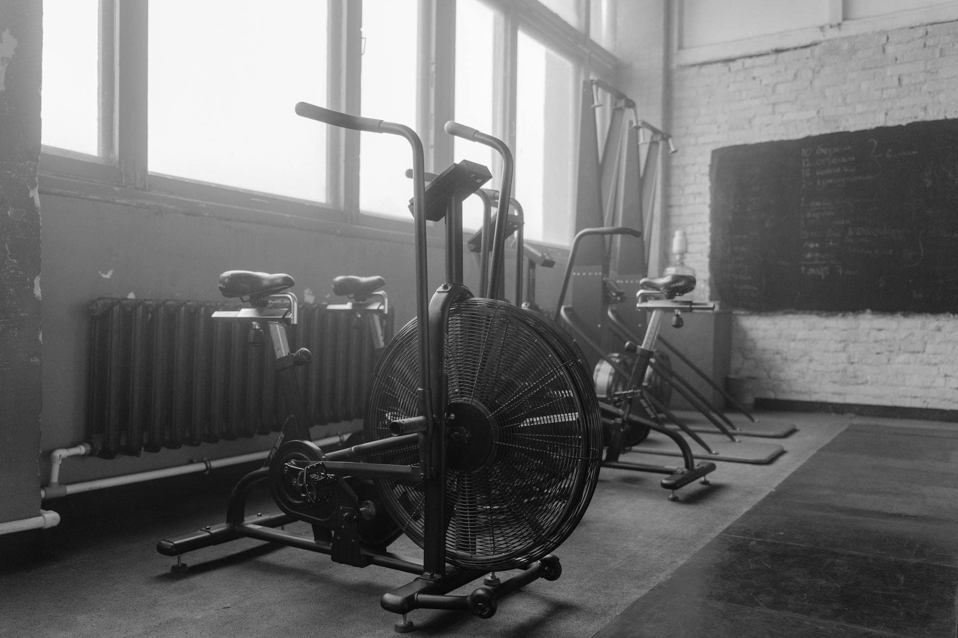 Black and white gym interior featuring exercise bikes and fitness equipment. - no equipment cardio workout