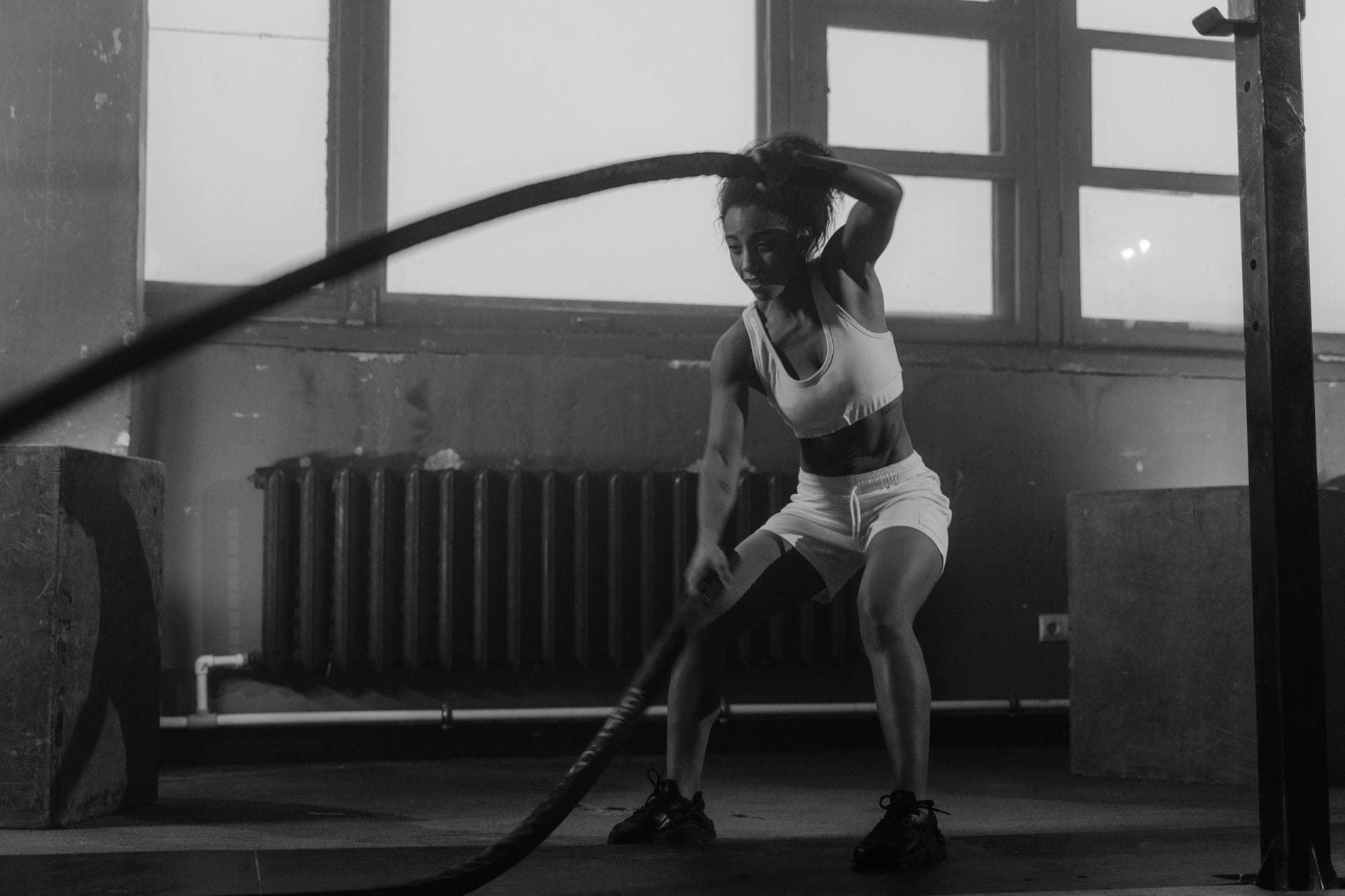 Woman in a gym engaging in vigorous battle rope workout for fitness. - fat burning workouts