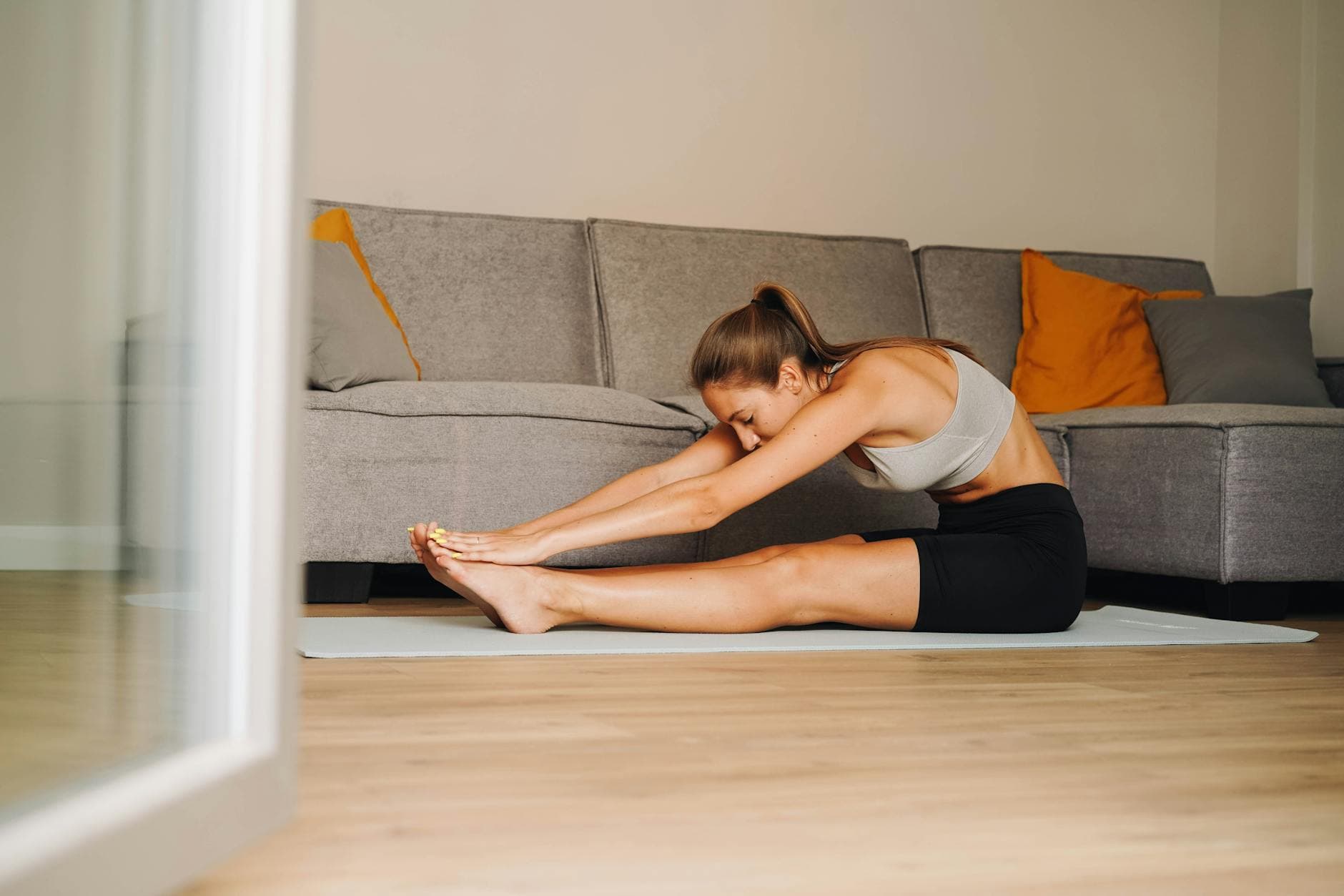 Woman in activewear stretching on yoga mat at home, promoting a healthy lifestyle. - flexibility stretching routine