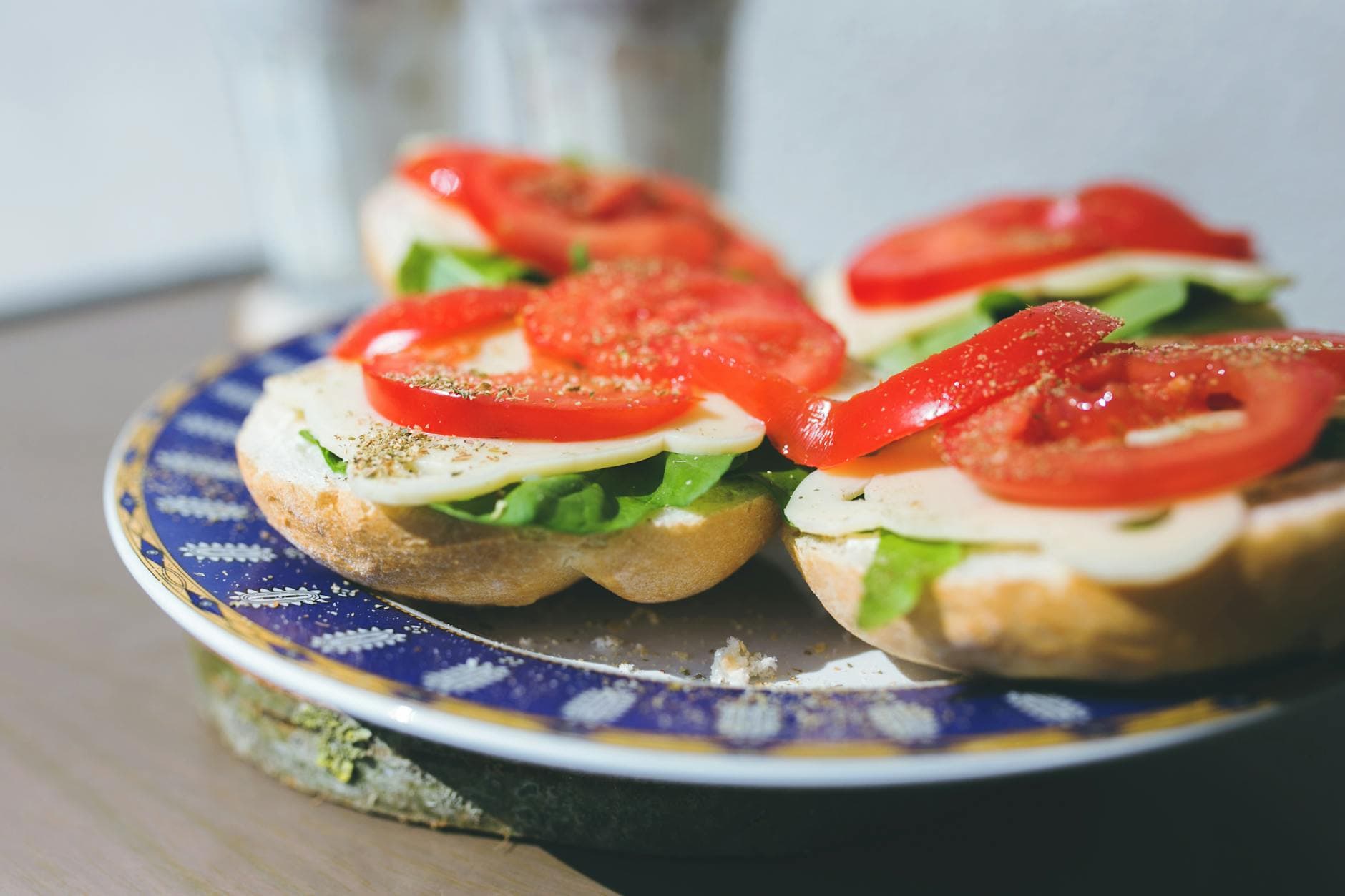 Close-up of vegetarian sandwiches with cheese, lettuce, and tomato on a decorative plate. - healthy breakfast sandwich