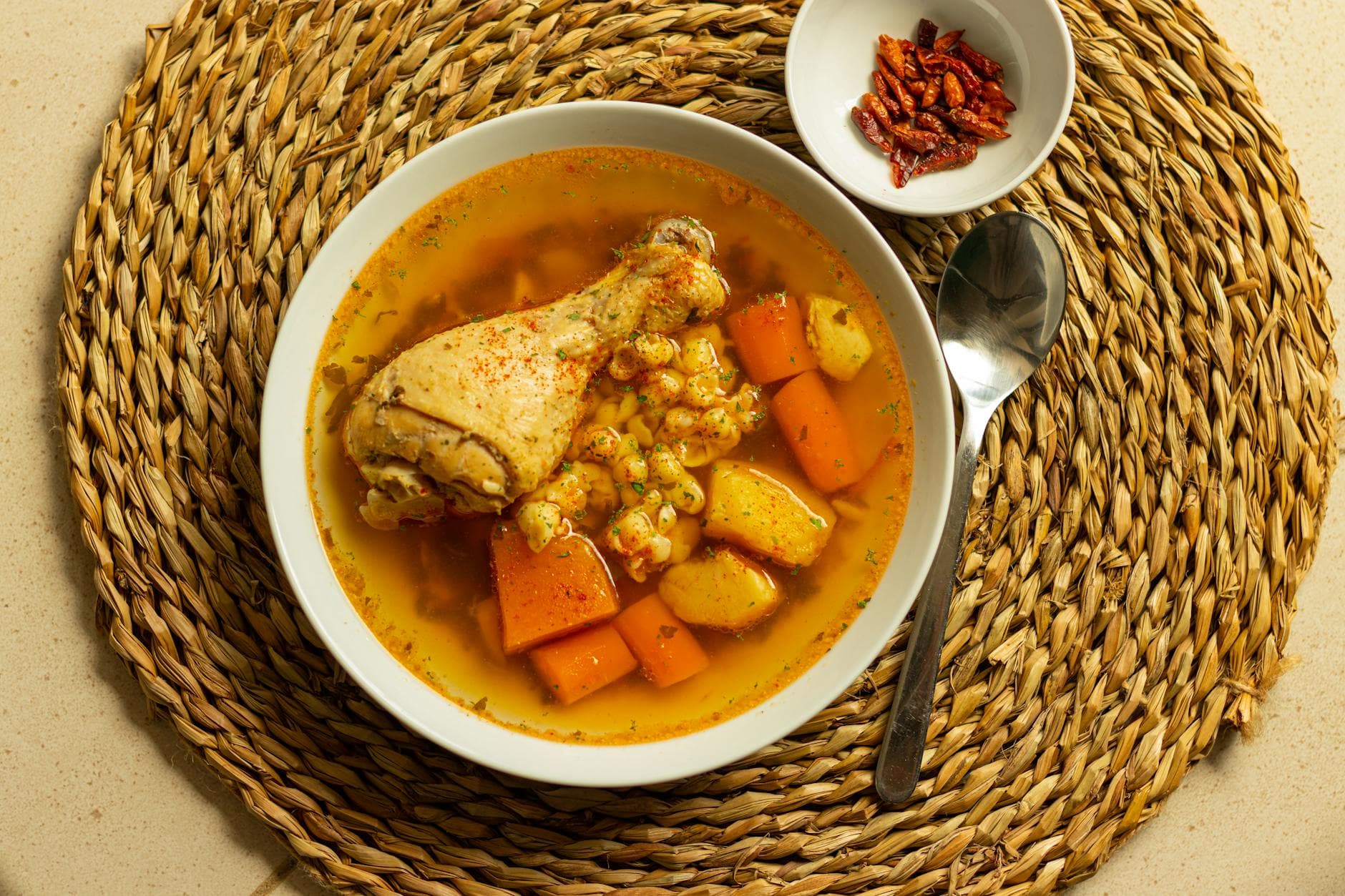 A comforting chicken and vegetable soup served in a bowl with a spoon on a woven mat. - healthy chicken recipes