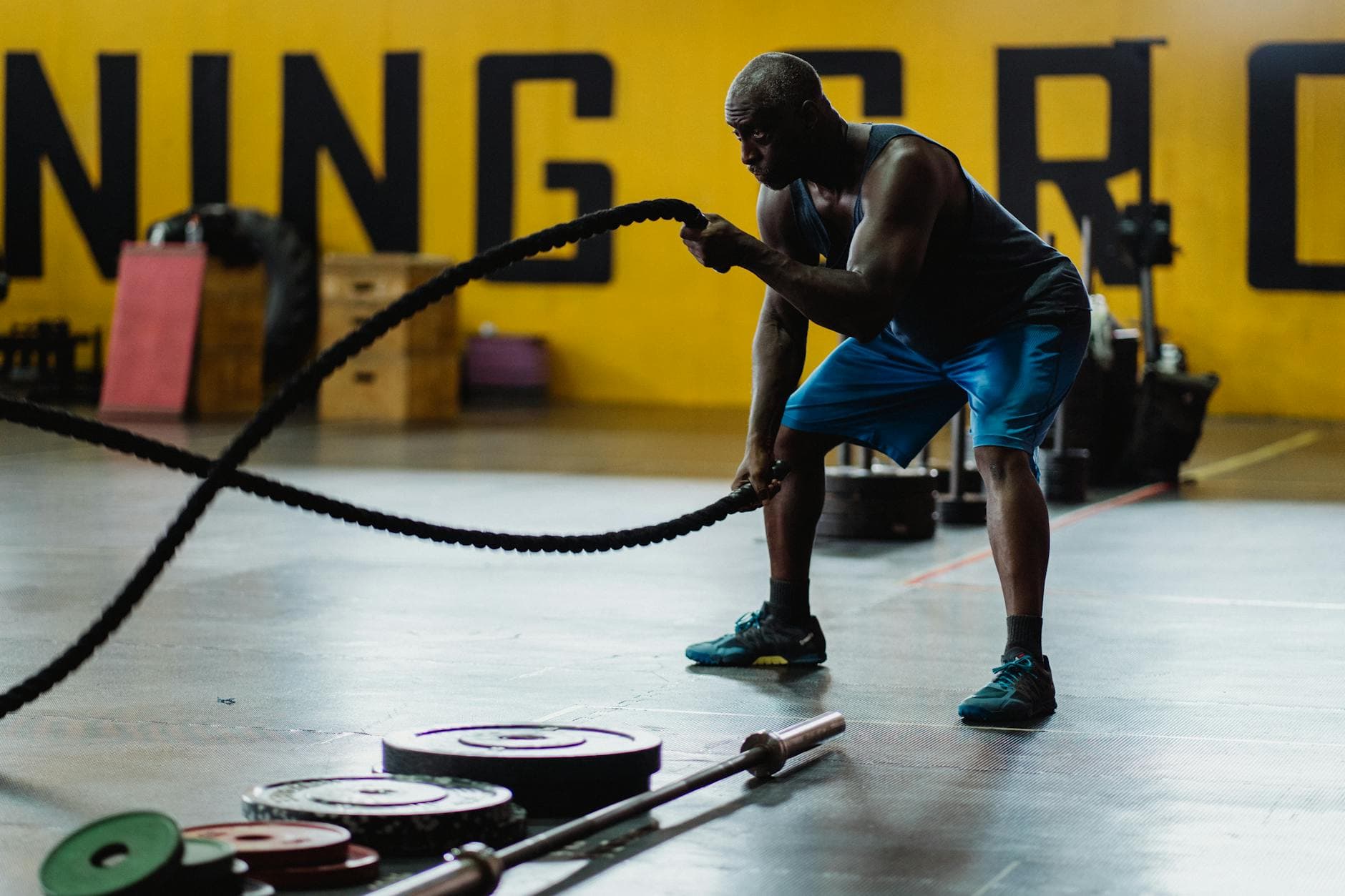 Brawny man exercising with battle ropes in a gym, showcasing strength and focus. - high intensity interval training