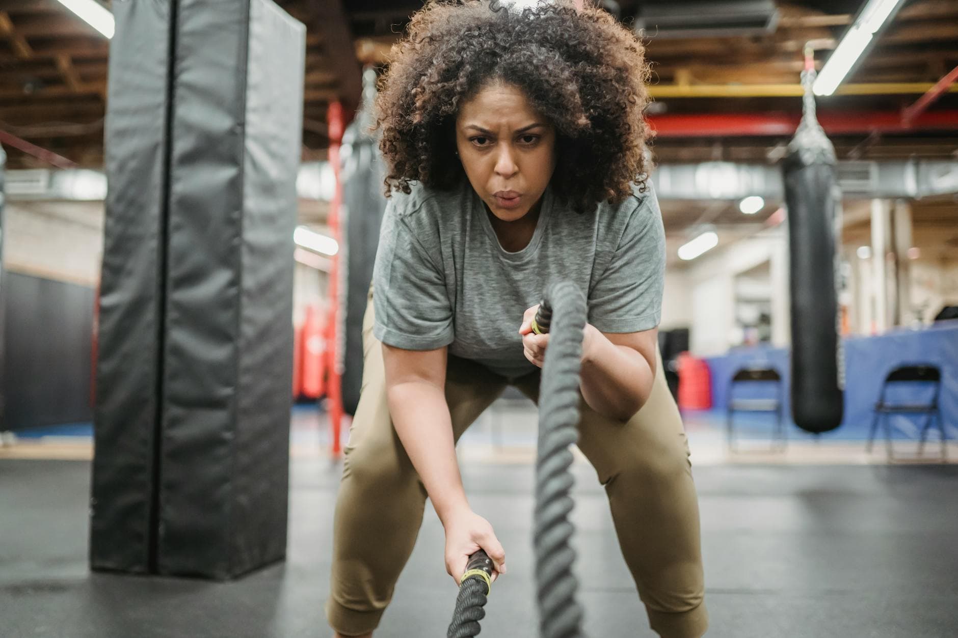 A determined woman performing a high-intensity battle rope exercise in a gym, showcasing strength and focus. - hiit cardio workout