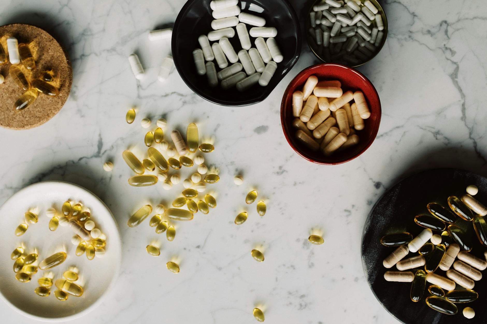 Assorted capsules and pills on a marble surface, illustrating healthcare and medication themes. - magnesium supplement benefits