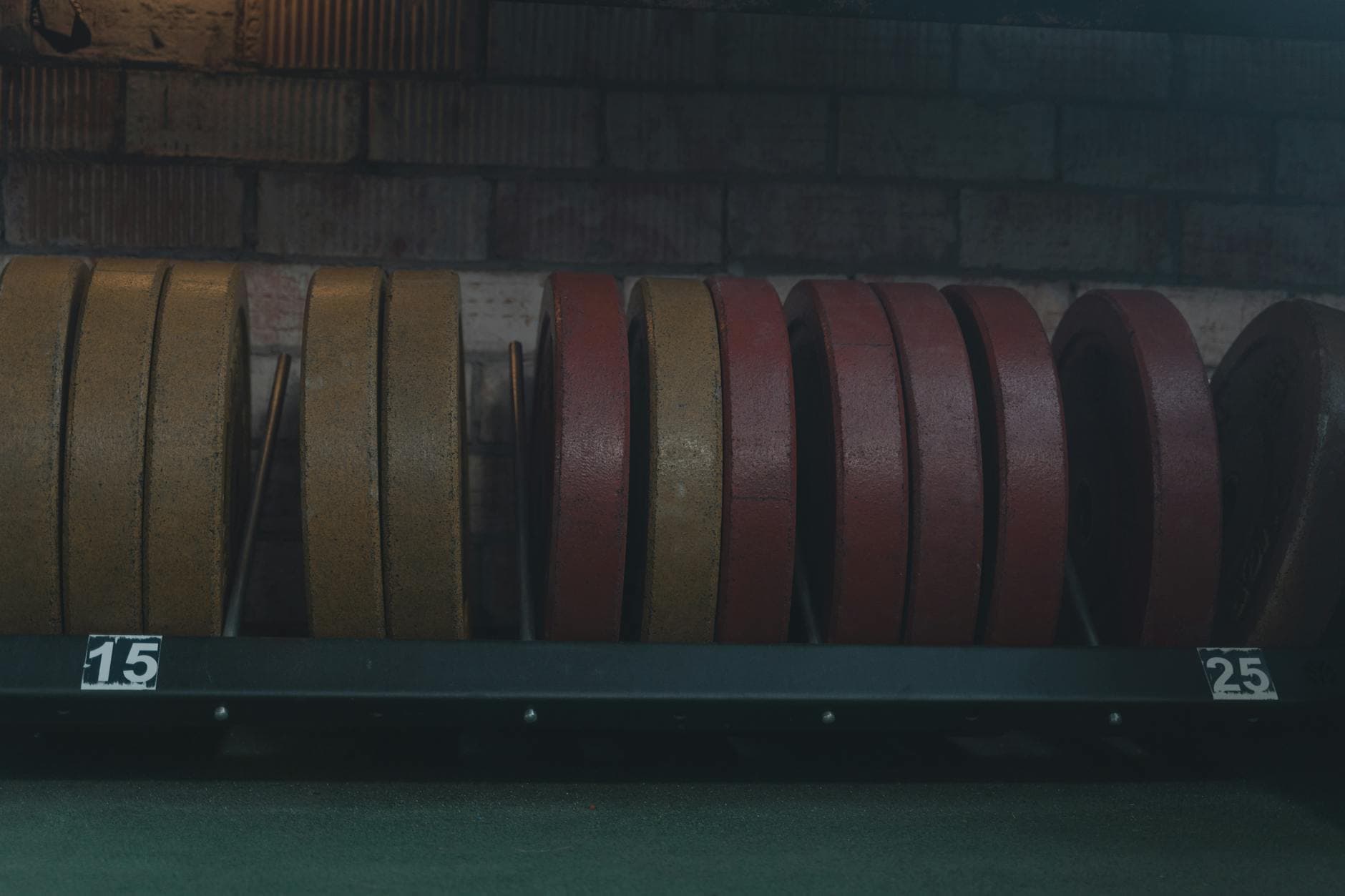 Detailed view of gym weight plates on a rack in an indoor fitness center. - maintain weight travel