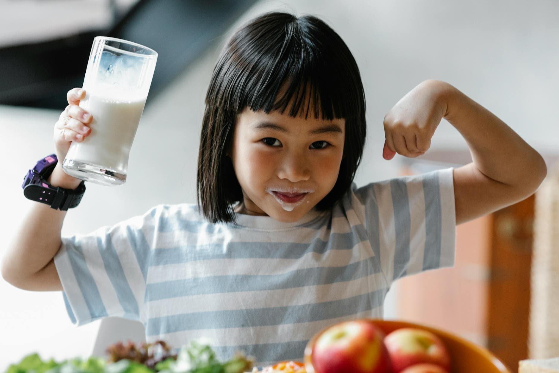 A happy child drinking milk and flexing muscles, promoting a healthy breakfast habit. - morning exercise kids