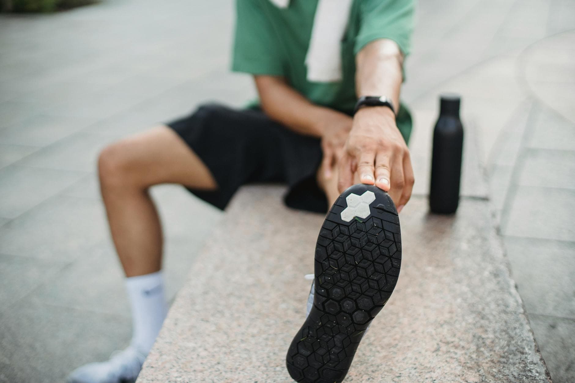 Young man in sports clothing stretching outdoors, equipped with a towel and water bottle. - morning muscle activation
