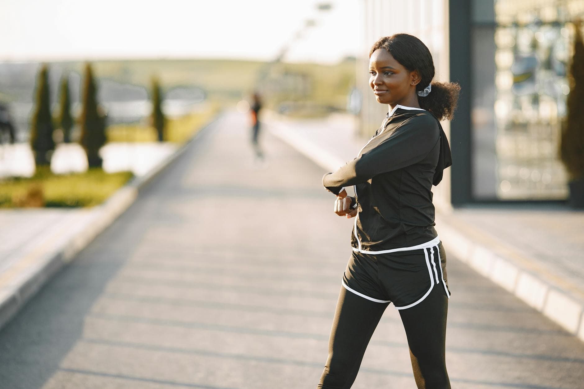 Woman in activewear stretches on a sunny morning outdoors, promoting wellness. - morning stretch routine
