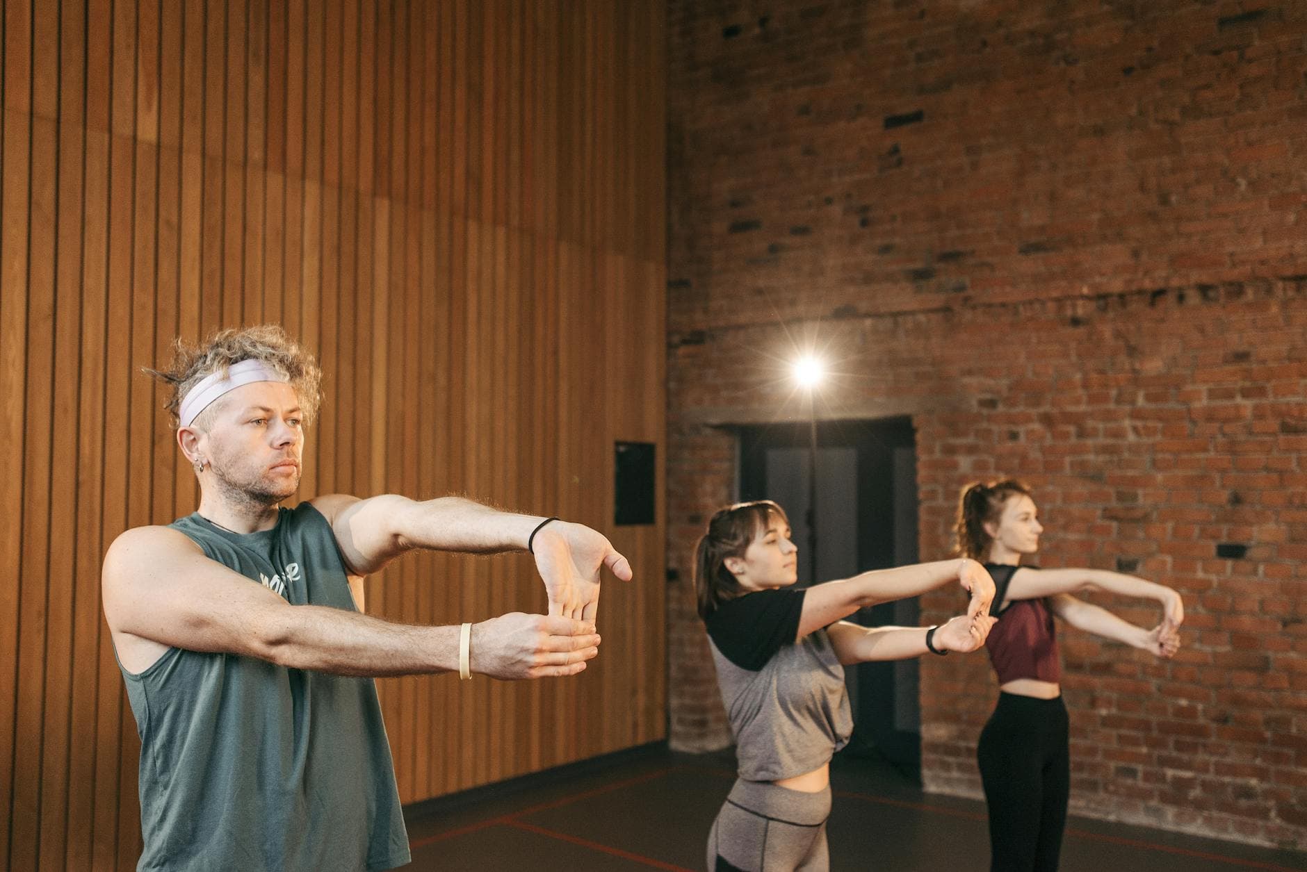 A diverse group of adults stretching in a contemporary fitness studio with a wooden accent wall. - neck posture exercises