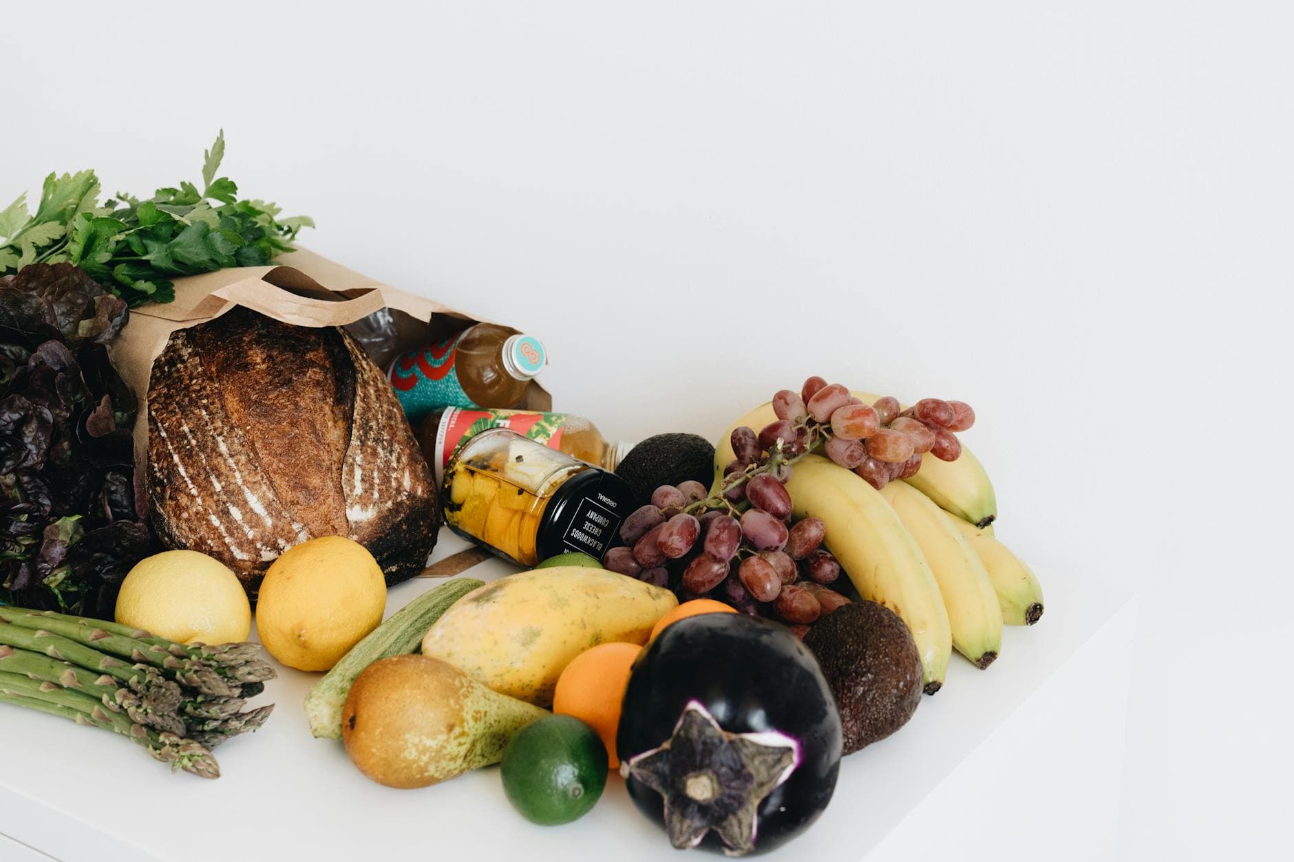 A colorful assortment of fresh fruits and vegetables including bread and organic produce on a white background. - potassium rich foods