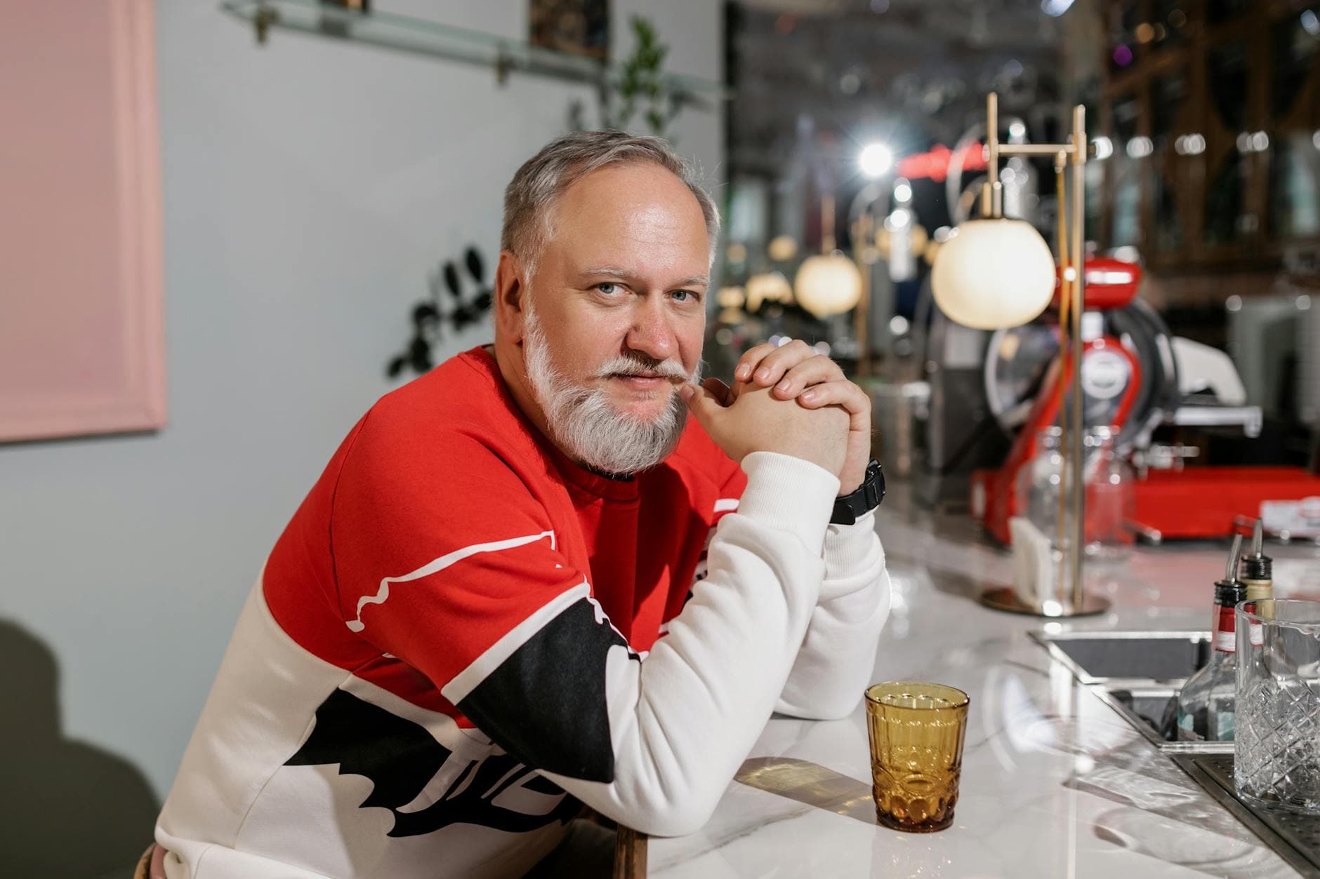 Senior man with beard sitting at a modern bar, sporting a stylish look and casual attitude. - seated good morning