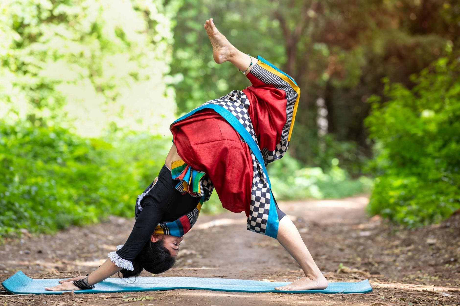 Woman practicing yoga outdoors in vibrant traditional clothing, showcasing flexibility and harmony with nature. - spring yoga flow