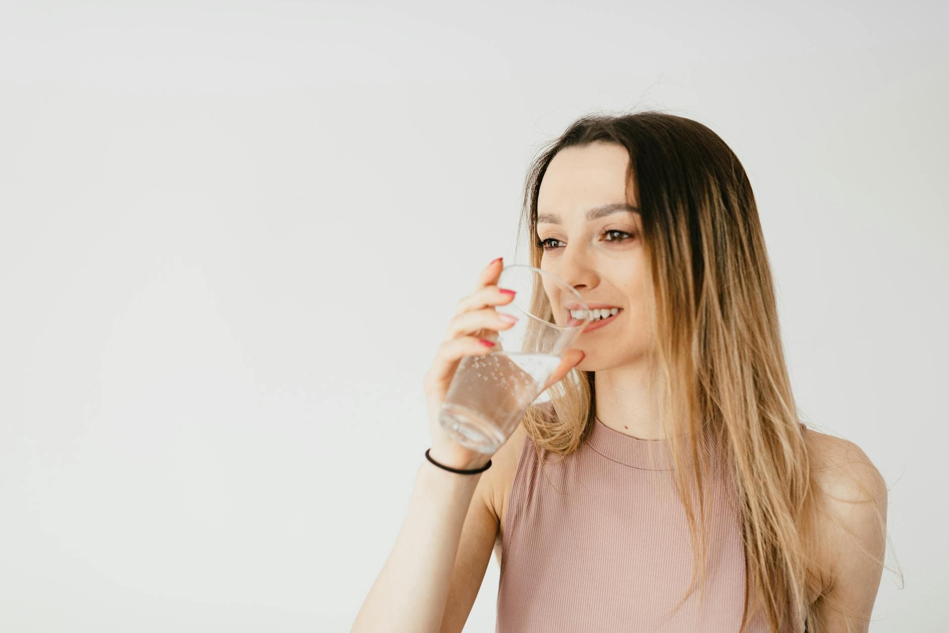 Young woman happily drinking a glass of water for healthy hydration. - water fast cleanse
