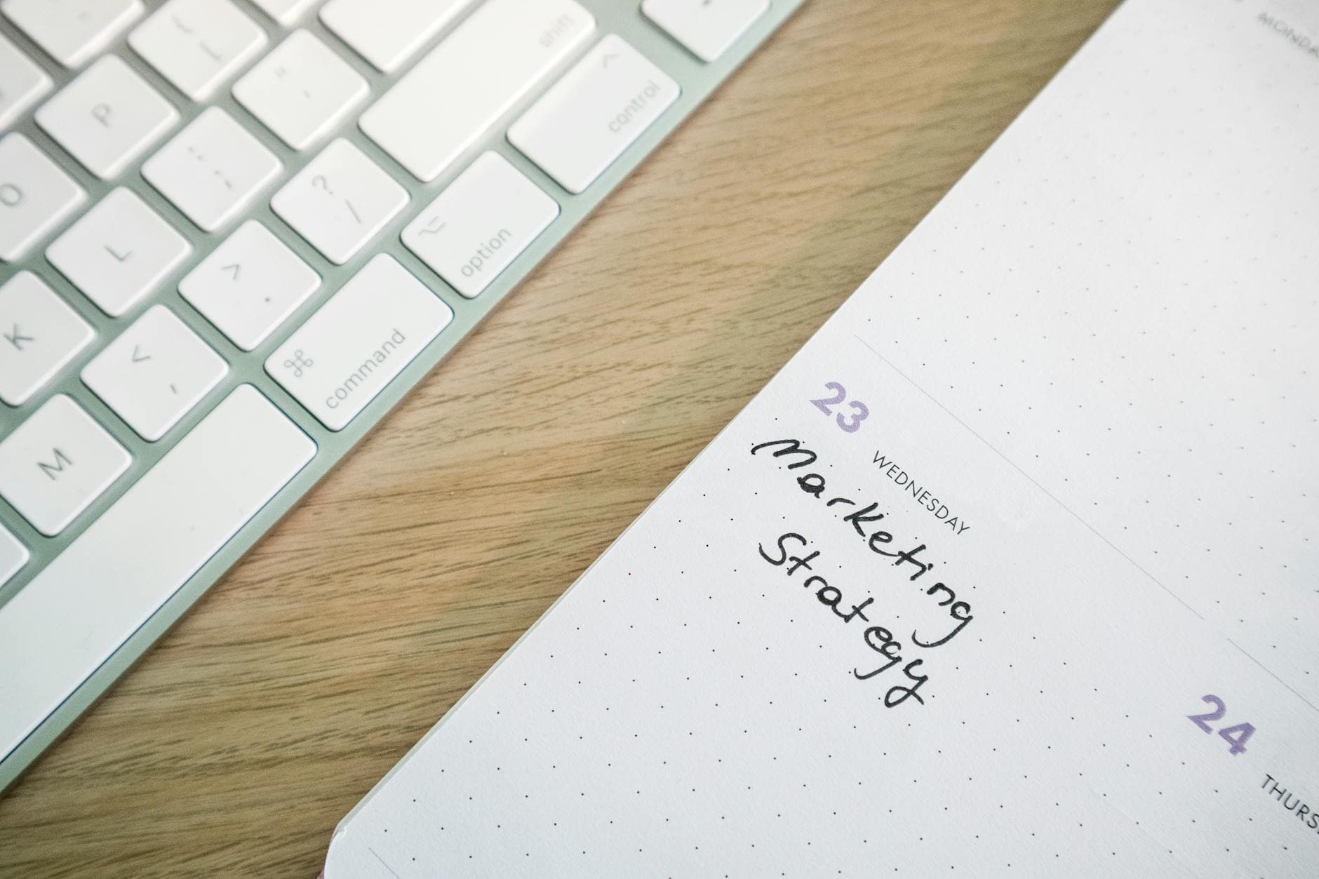 Close-up of a desk with a keyboard and a calendar open to a marketing strategy note. - weekly workout plan