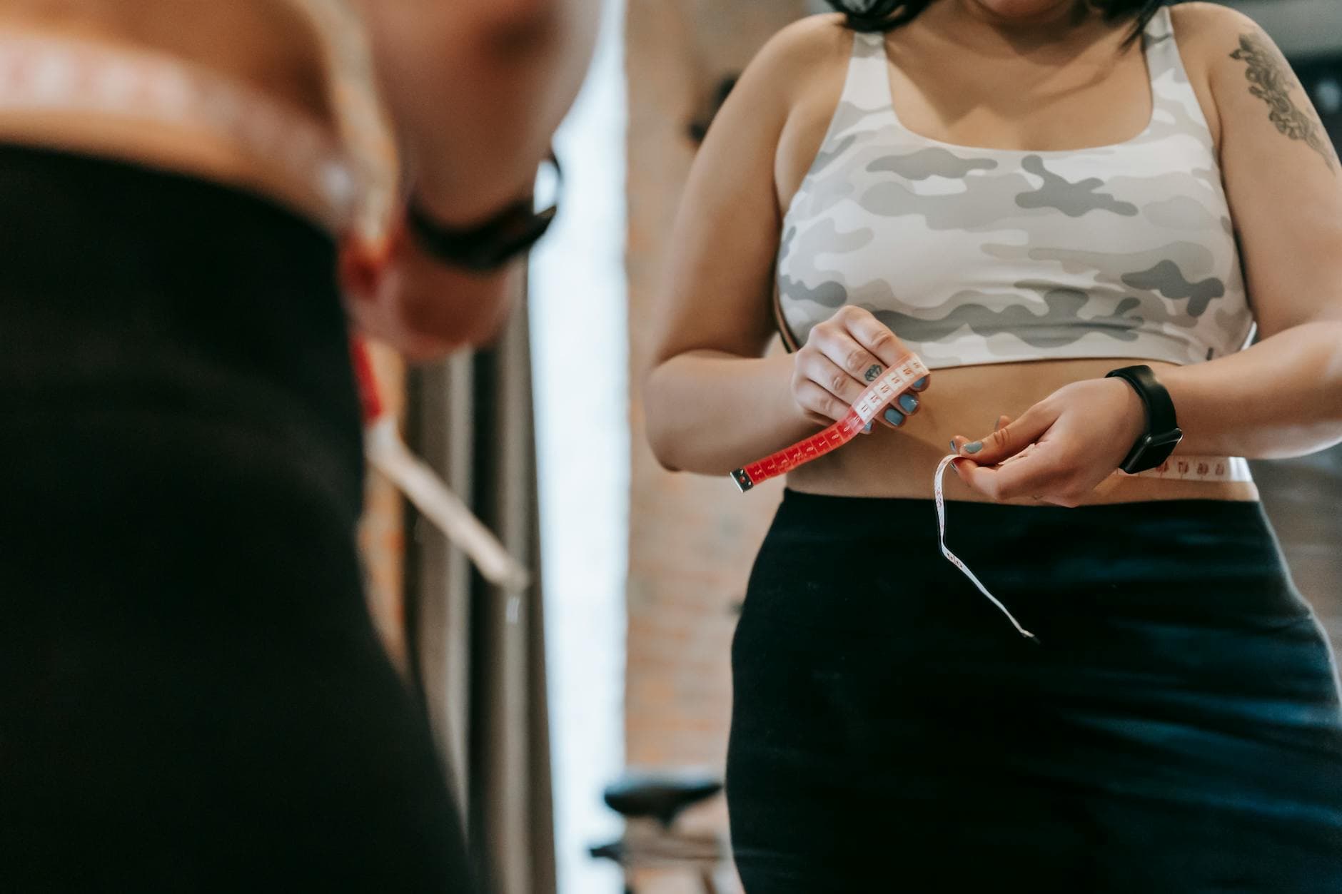 Low angle of crop faceless overweight female in activewear reflecting in mirror in sports club - calorie deficit for weight loss
