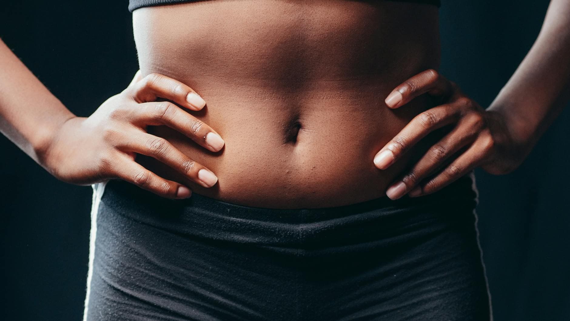 A close-up shot of hands on an athletic abdomen, symbolizing fitness and health. - fat burning abs