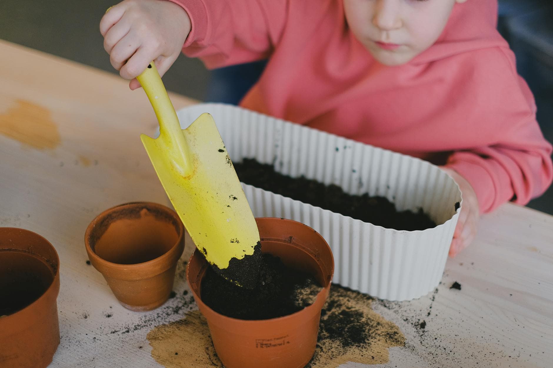 Young child engaged in planting using clay pots and soil, learning gardening basics. - gardening for health