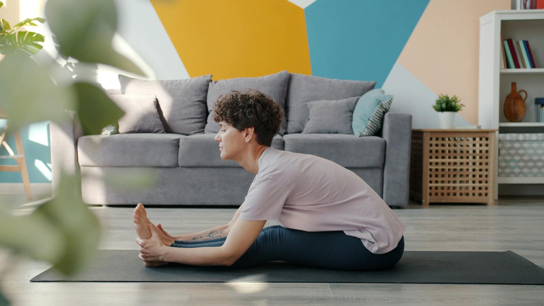 Person practicing yoga in a stylish living room with geometric wall design. - home wellness retreat