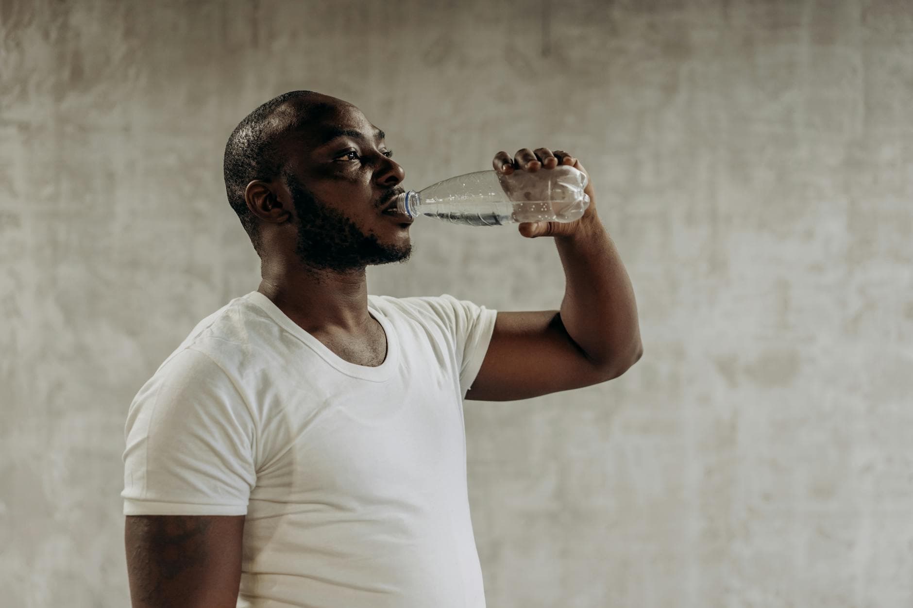 Healthy living concept: Man staying hydrated with water. Indoors, fitness focus. - spring hydration plan