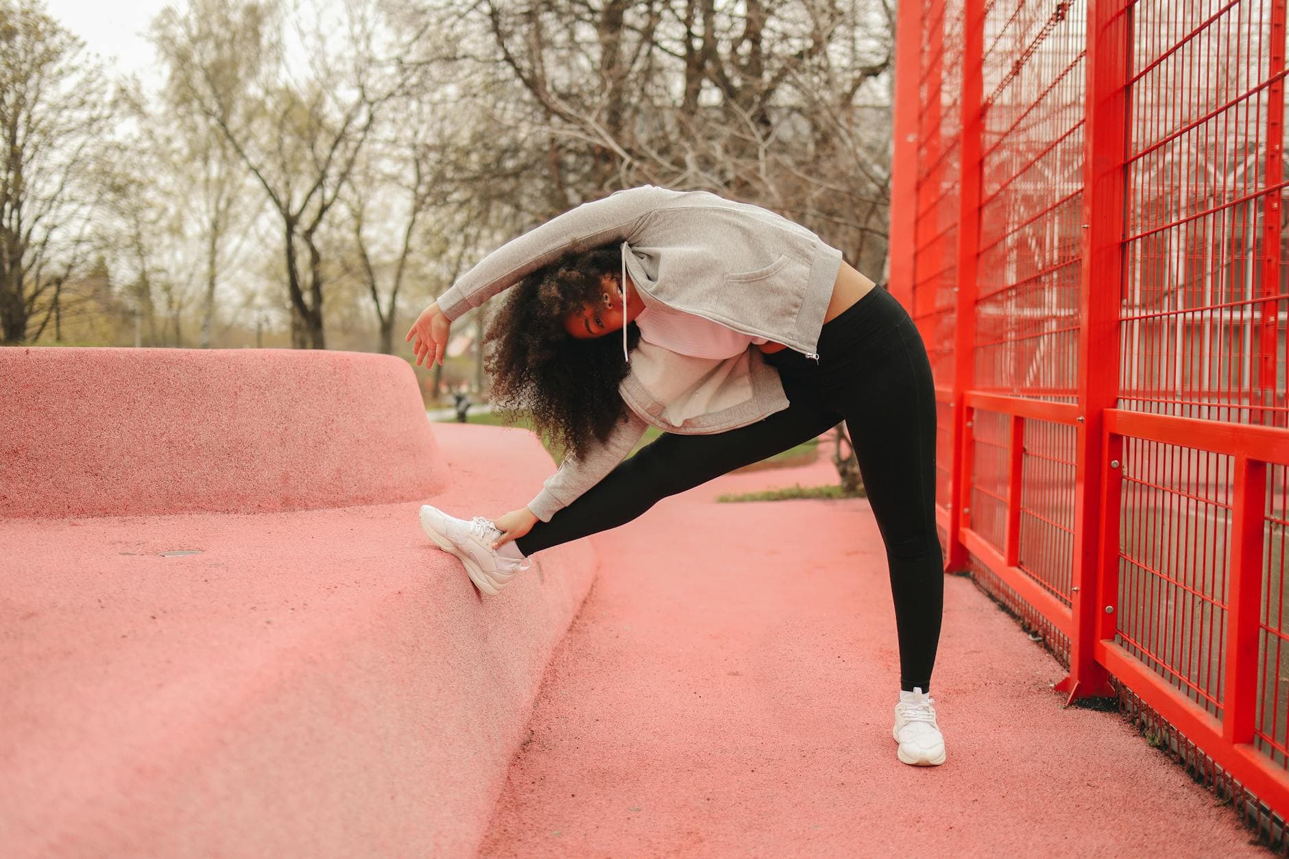 Woman stretching outdoors against a bright red structure, promoting fitness and wellness. - spring outdoor exercise mental health