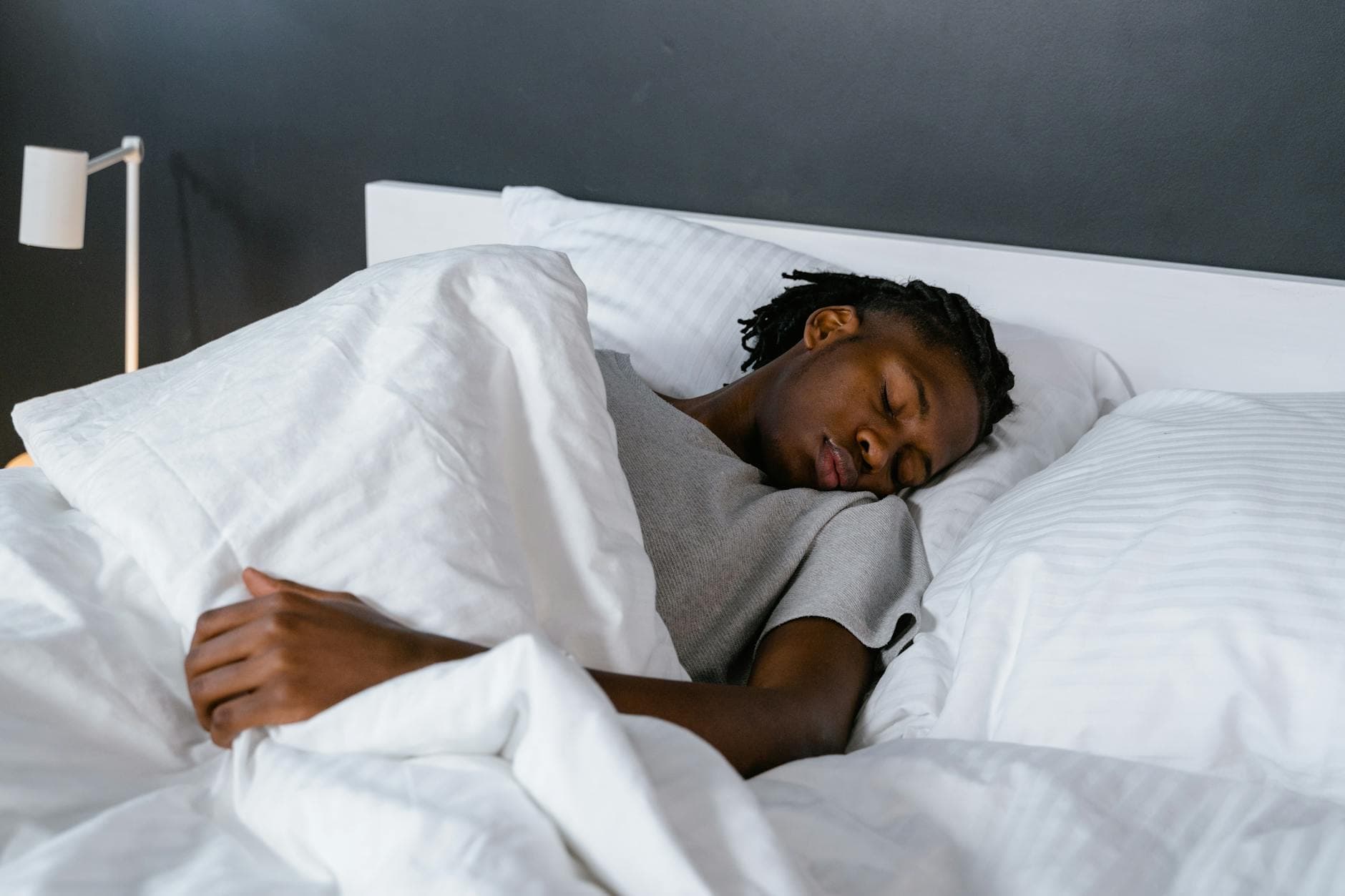 A serene scene of a young adult sleeping in a cozy bedroom, emphasizing relaxation and comfort. - spring sleep reset