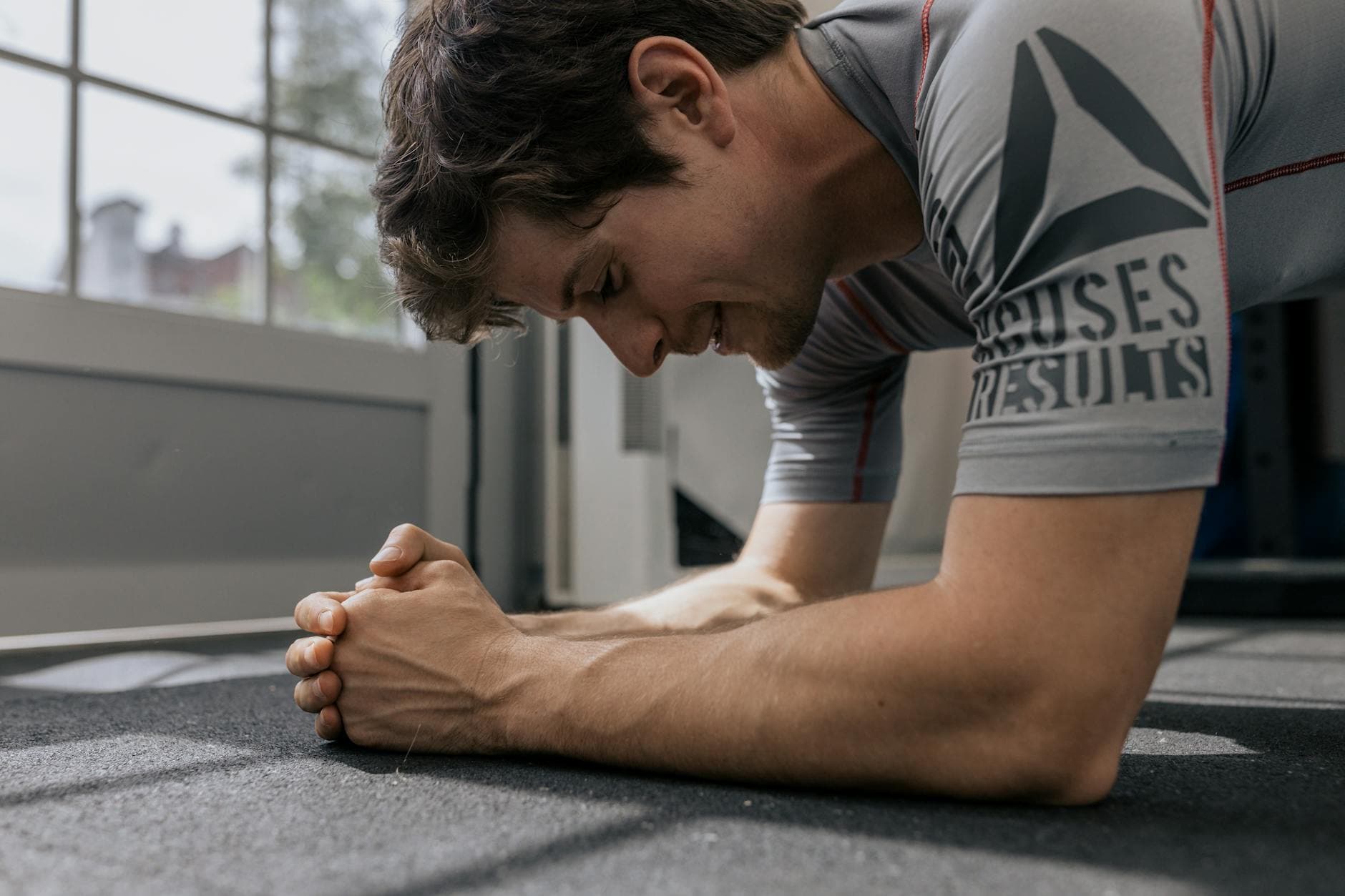 Focused man doing a plank exercise inside a gym for a core workout. - advanced core exercises