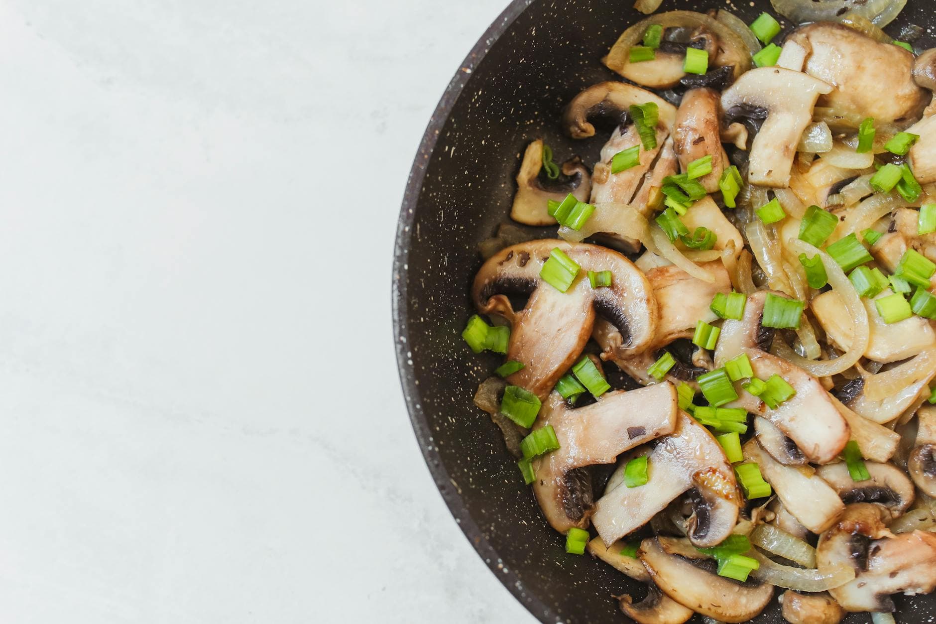 Top-down view of sautéed mushrooms and spring onions in a frying pan. - easy vegan recipes