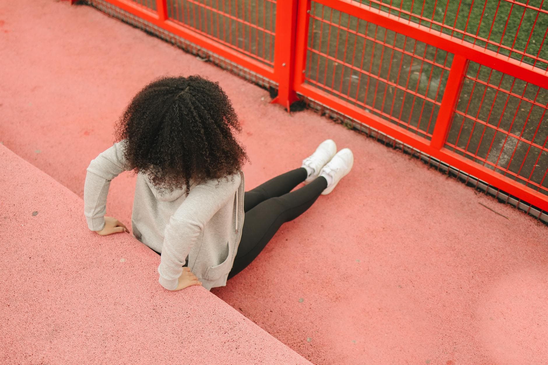 A woman performs outdoor exercises on a vibrant red surface, showcasing fitness and style. - outdoor cardio workouts