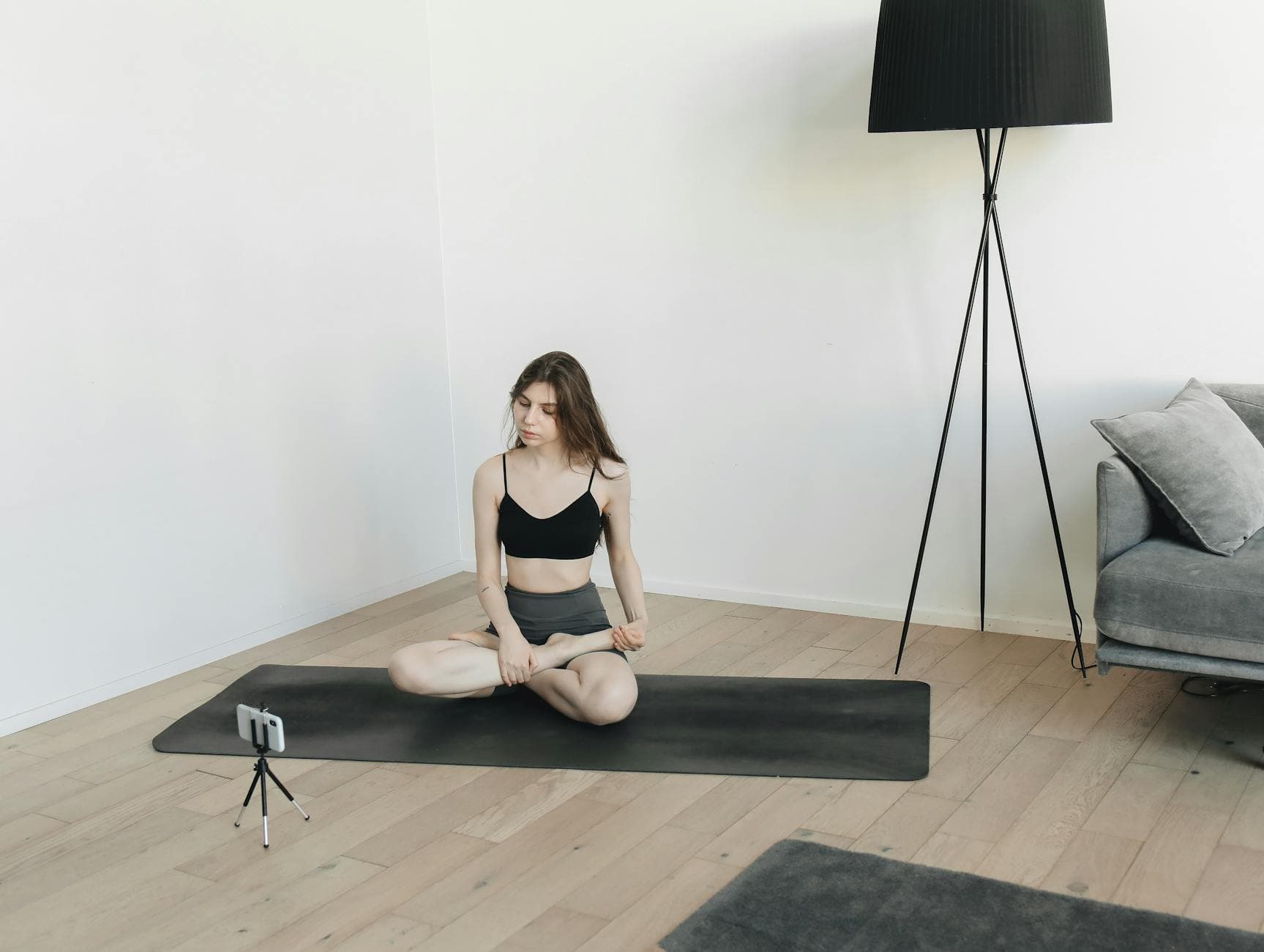 A woman practicing a yoga pose indoors with a smartphone for online vlogging. - beginner yoga classes online
