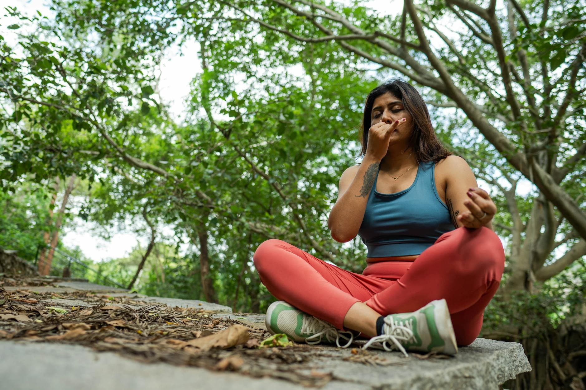 Young woman meditating in a forest, practicing yoga breathing exercises on a stone platform. - deep breathing exercises