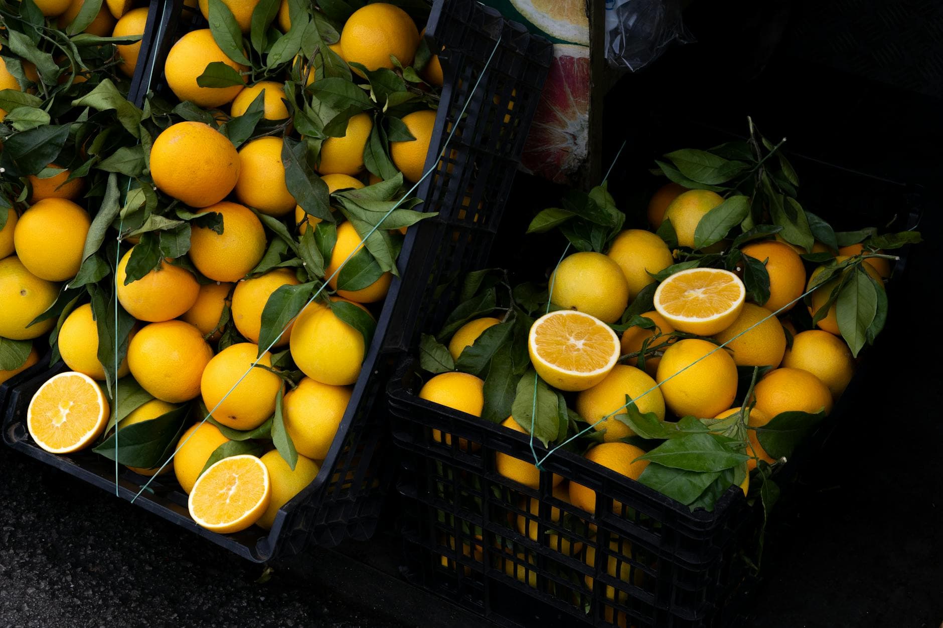 Freshly harvested oranges in crates with green leaves at a market in Rome, Italy. - lemon water benefits
