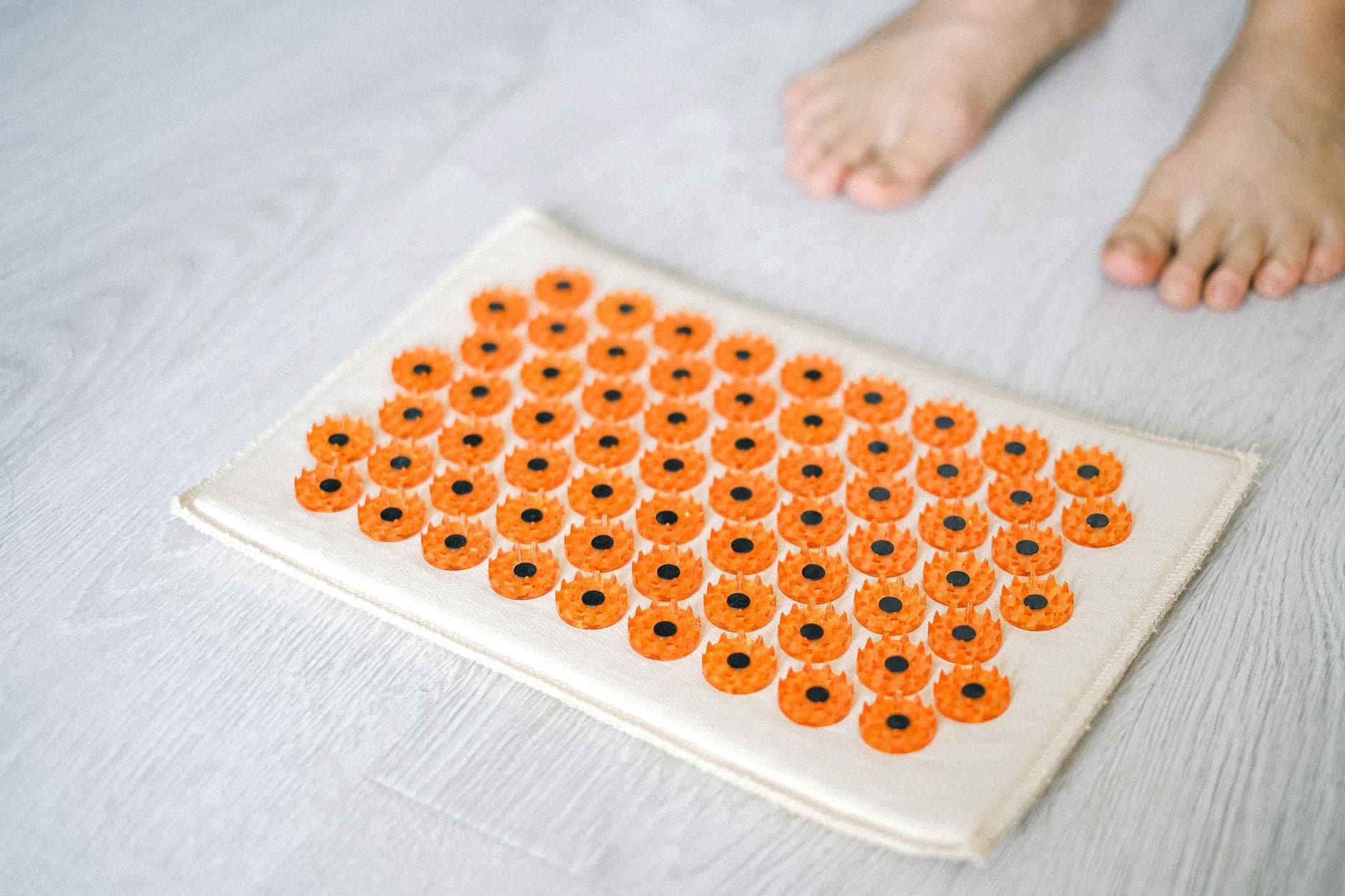 Close-up of a foot acupressure mat on a wooden floor, ideal for relaxation therapies. - sciatica pain relief