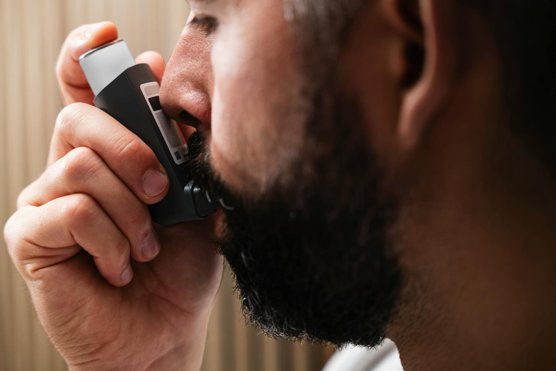 A close-up image of a man using an inhaler, highlighting respiratory health concepts. - spring allergy relief