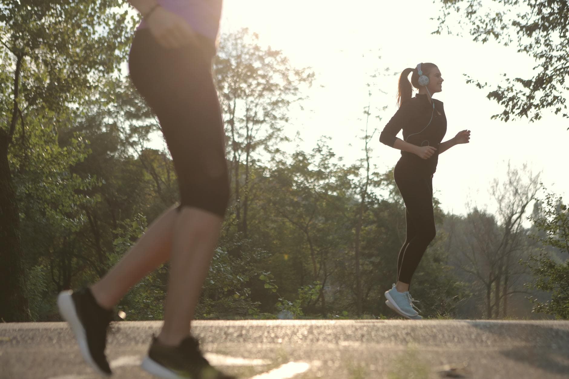 Two women jogging in a sunny park setting, enjoying a healthy morning exercise. - spring workout refresh