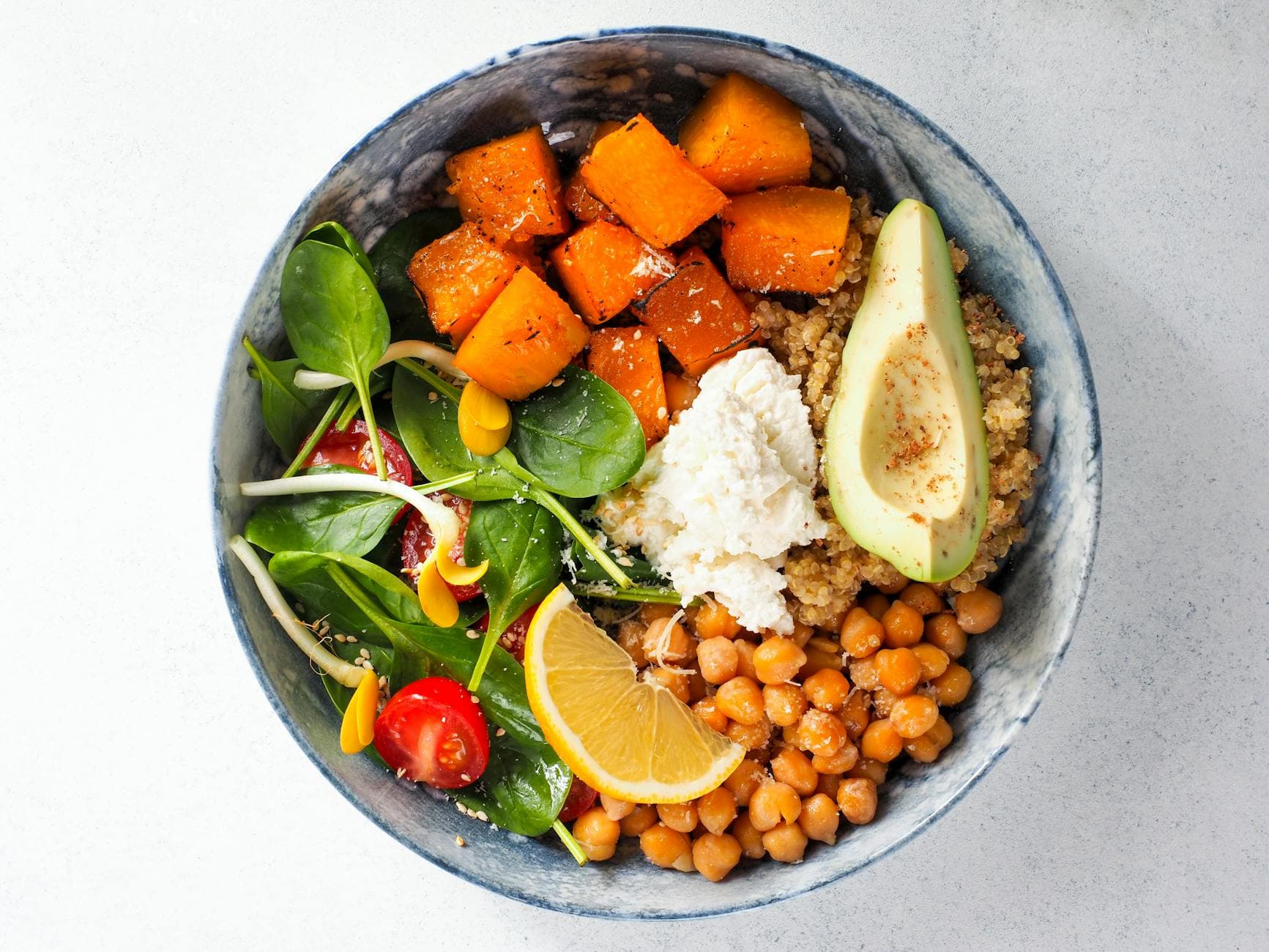 Top view of a colorful vegan buddha bowl featuring avocado, chickpeas, sweet potato, spinach, lemon, and quinoa. - allergy relief diet