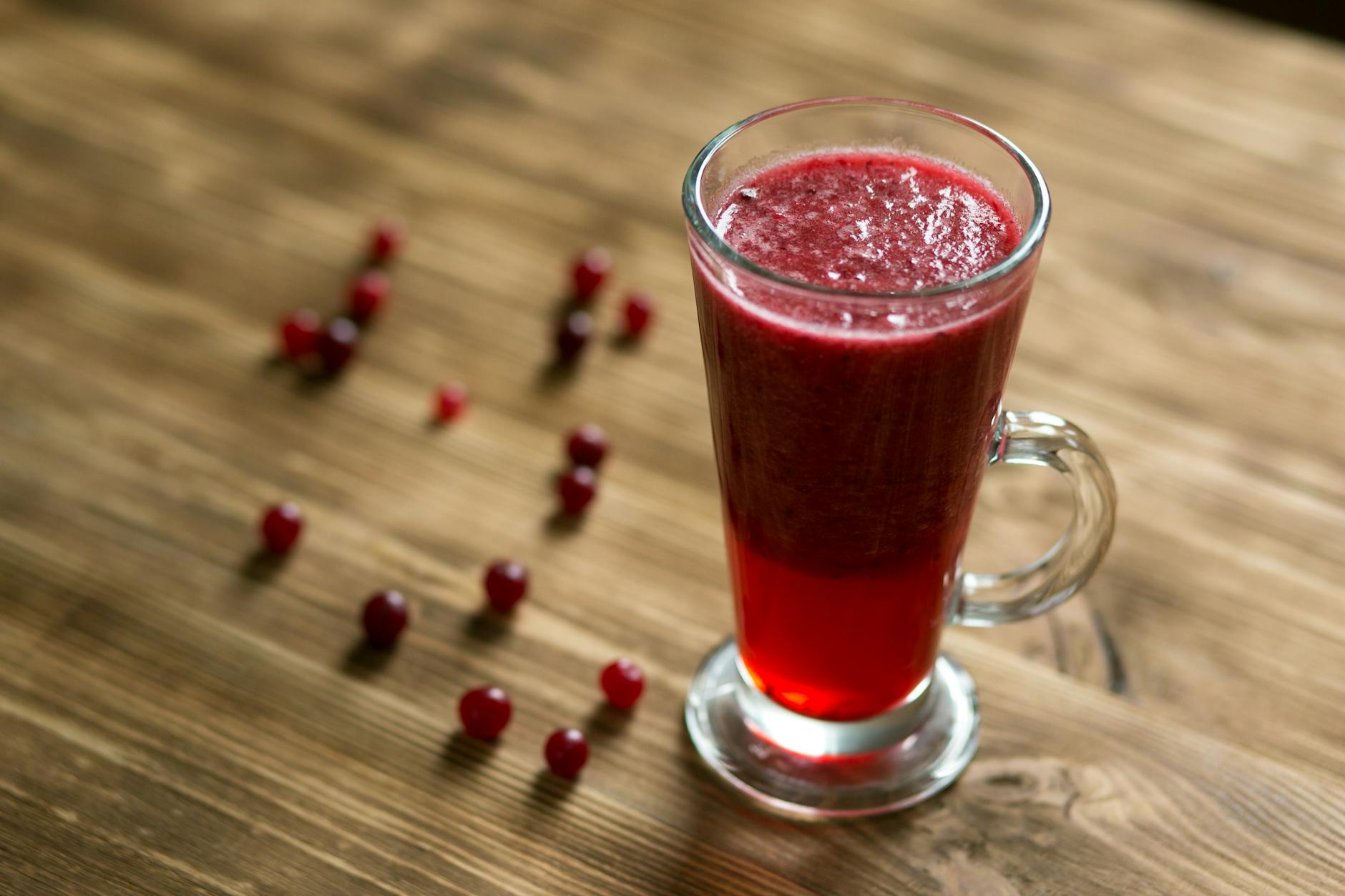 A tall glass of vibrant cranberry juice on a rustic wooden table. - anti inflammatory diet