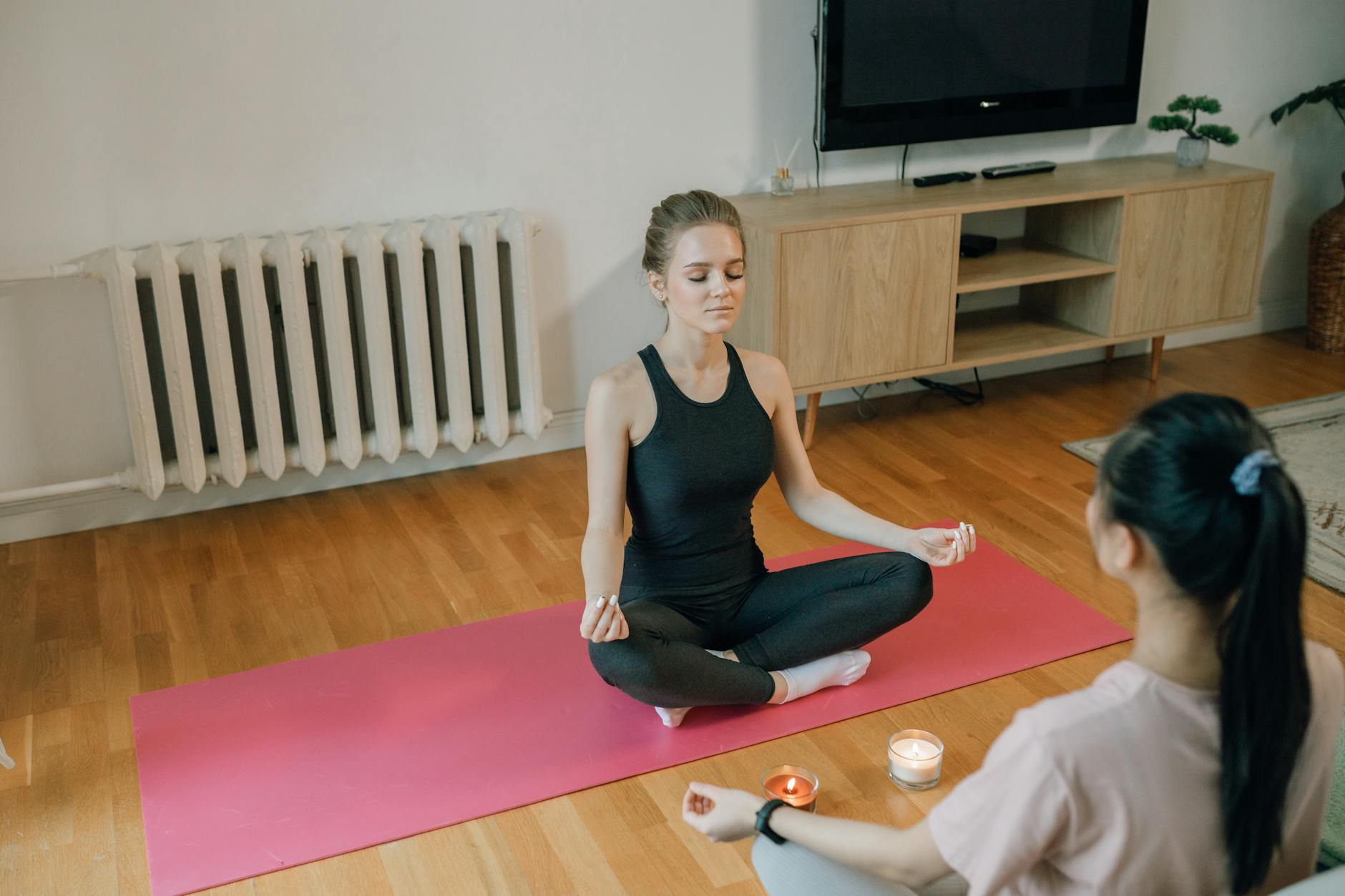 Two women meditating on a yoga mat indoors, practicing mindfulness and relaxation. - beginner yoga at home
