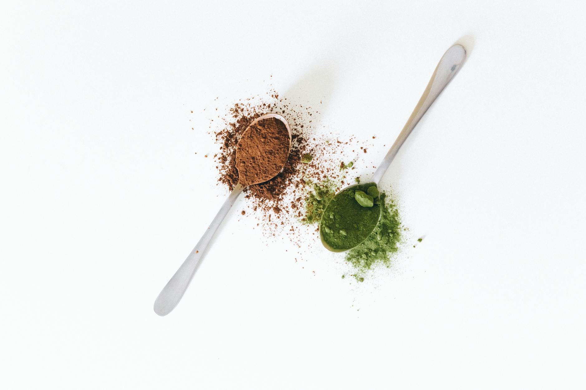 Close-up of spoons with cocoa and matcha powder on a white surface, perfect for food and health themes. - best plant based protein powder