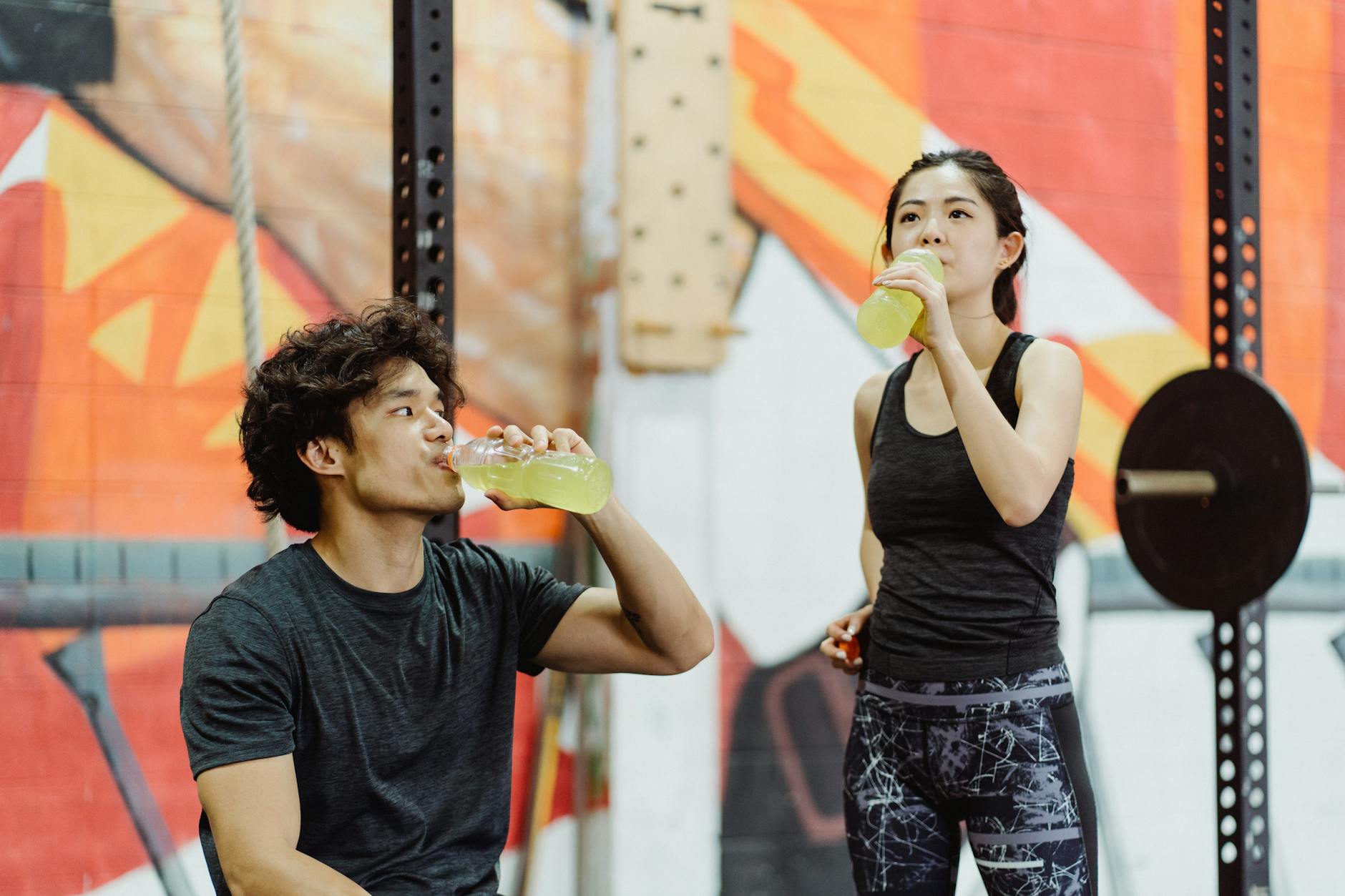 Couple in gym attire hydrating after a workout session indoors. - best post workout drink