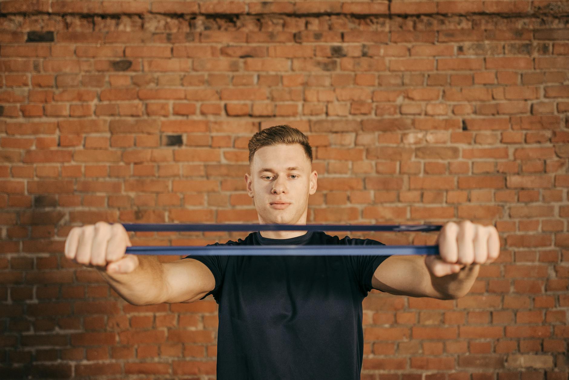 Man using resistance band against brick wall for fitness exercise. - best resistance band workout